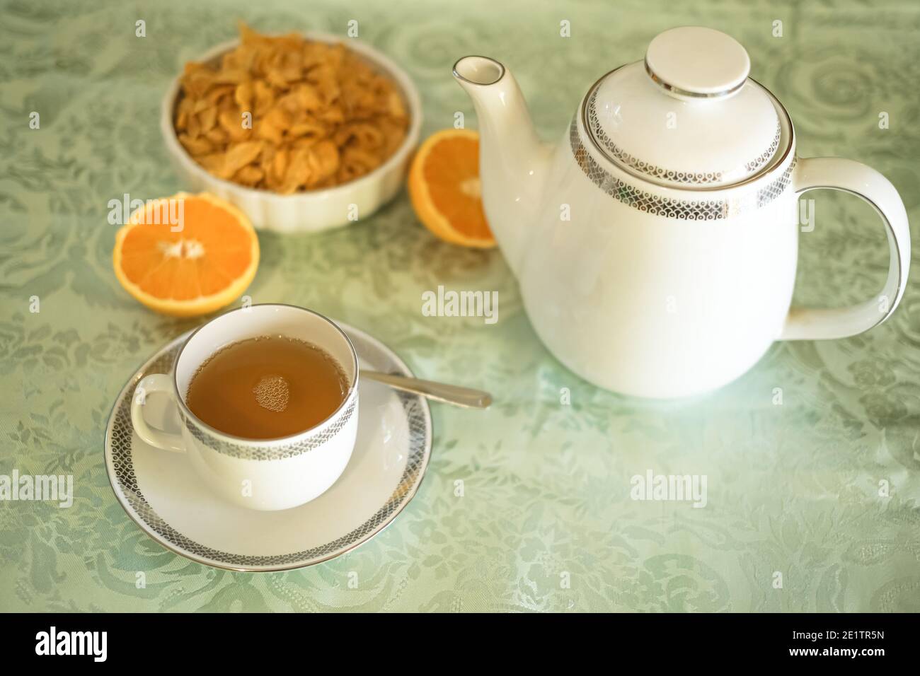 Gesunder Frühstückstisch mit heißem Tee, Müsli und frischen Orangen, morgendliche Heimreise Lifestyle Stockfoto