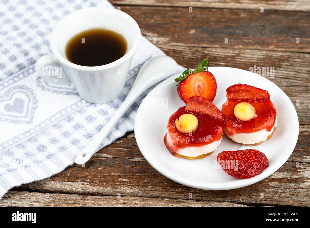 Weiße Tasse Espresso mit Erdbeeren und lila Blumen Auf einem Tisch bereit zum Frühstück italienische Gebäck Stockfoto