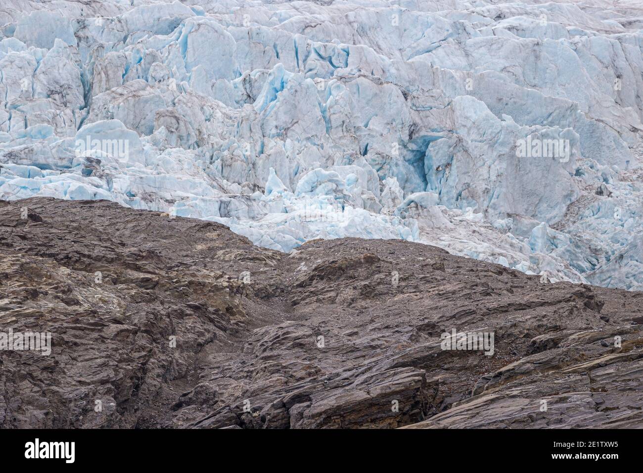 Eisbär ruht auf einer Berglinie, hoch oben auf einem Hügel bei Pyramiden auf Spitzbergen. Nordenskjoldbreen im Hintergrund. Stockfoto