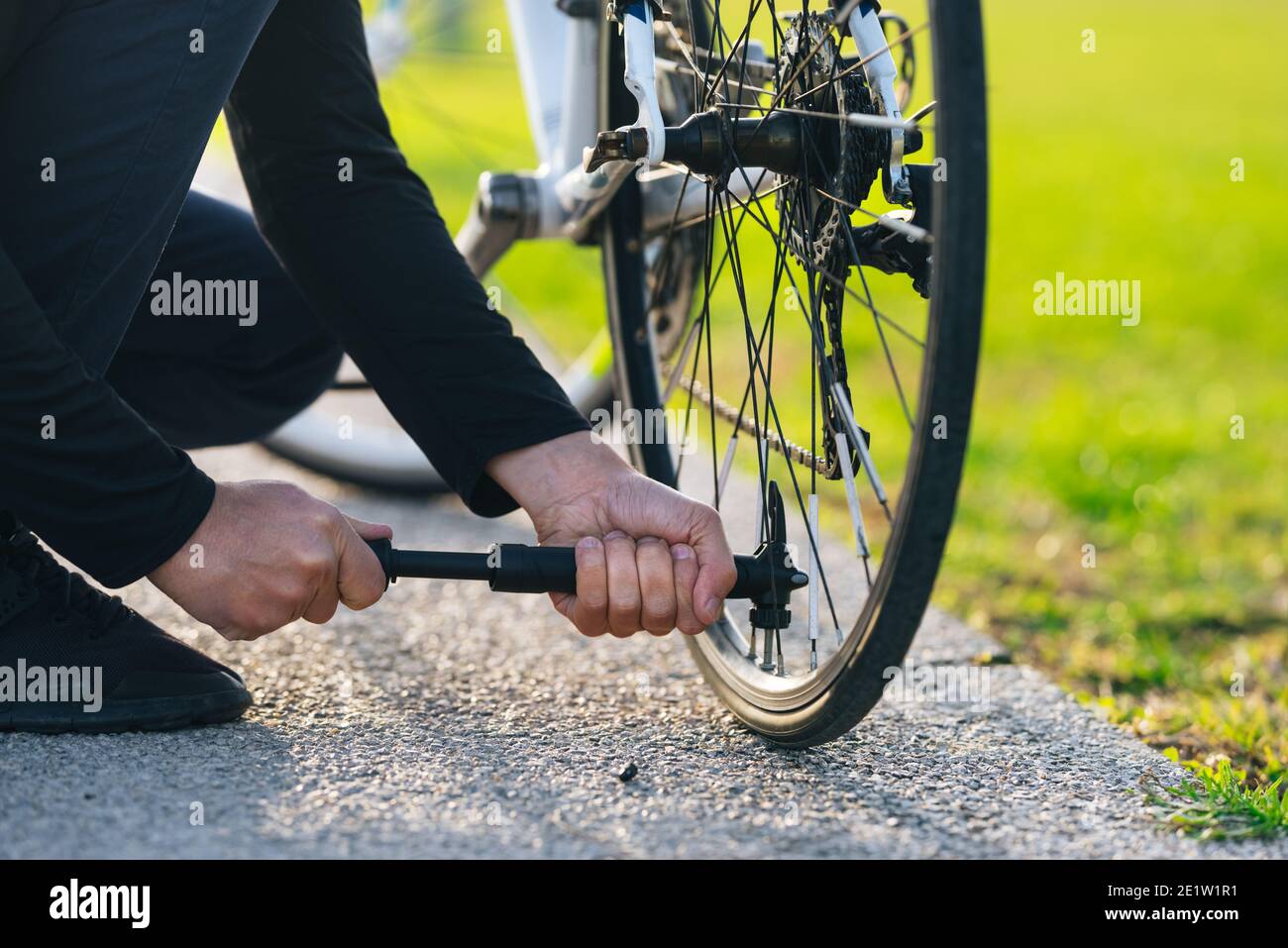 Mann pumpt Fahrrad Rad im Park. Der Mann pumpt das Rad mit einer Pumpe auf.  Pumpen von Luft in ein leeres Rad des Fahrrads Stockfotografie - Alamy