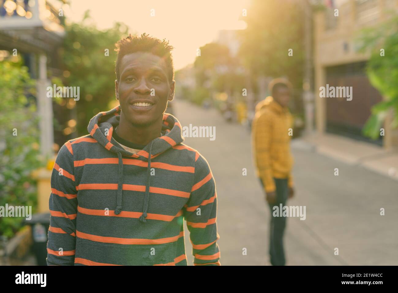 Junge glücklich Slim schwarz afrikanischer Mann lächelnd mit jungen schwarzen afrikanischen Mann an der Rückseite im Freien Stockfoto