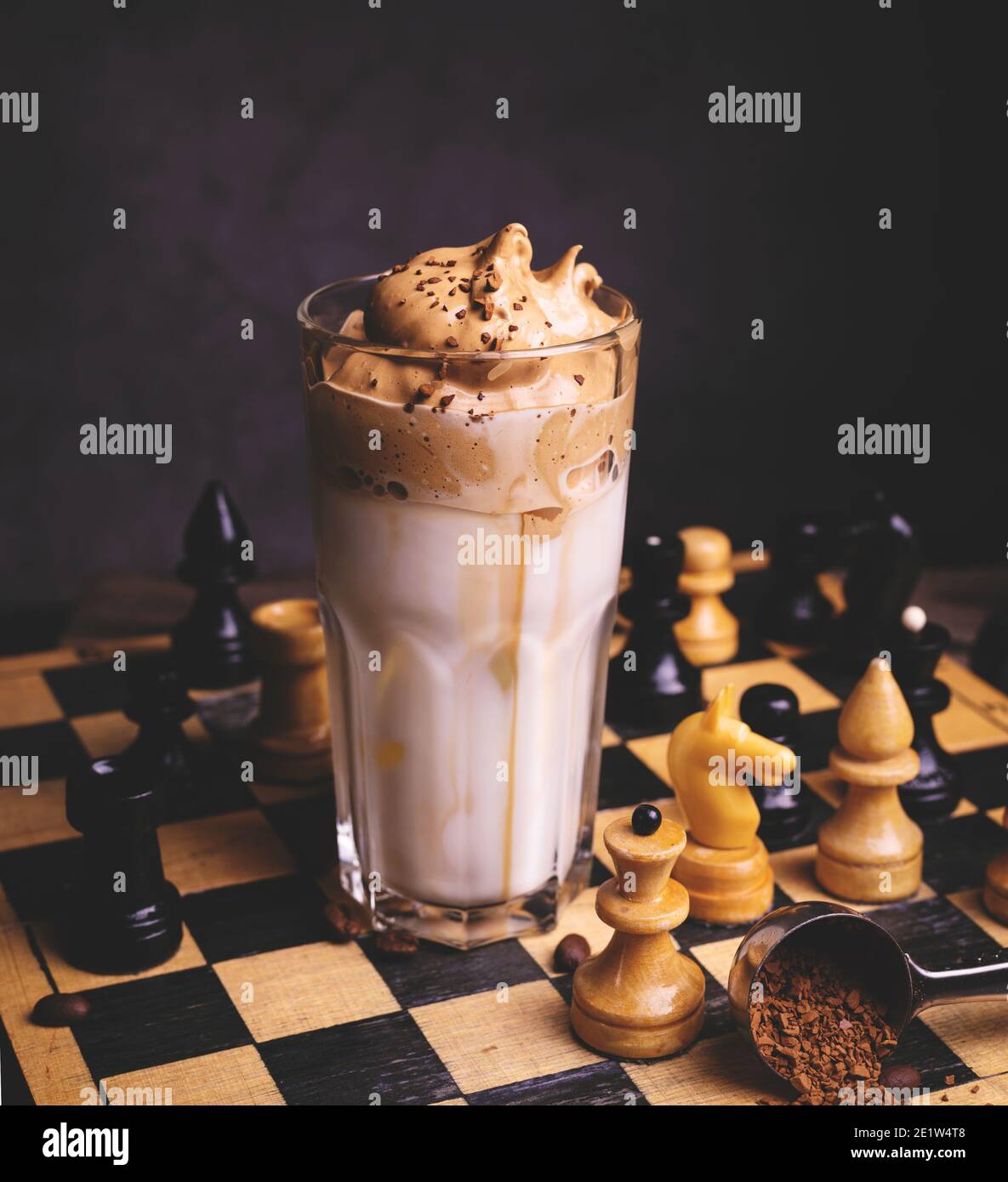 Dalgona Kaffee. Schlagsahngetränk mit Instant-Kaffee beliebt in Korea cremigen Cocktail in hohen Gläsern mit Schach auf Holzchessboard dekoriert Stockfoto