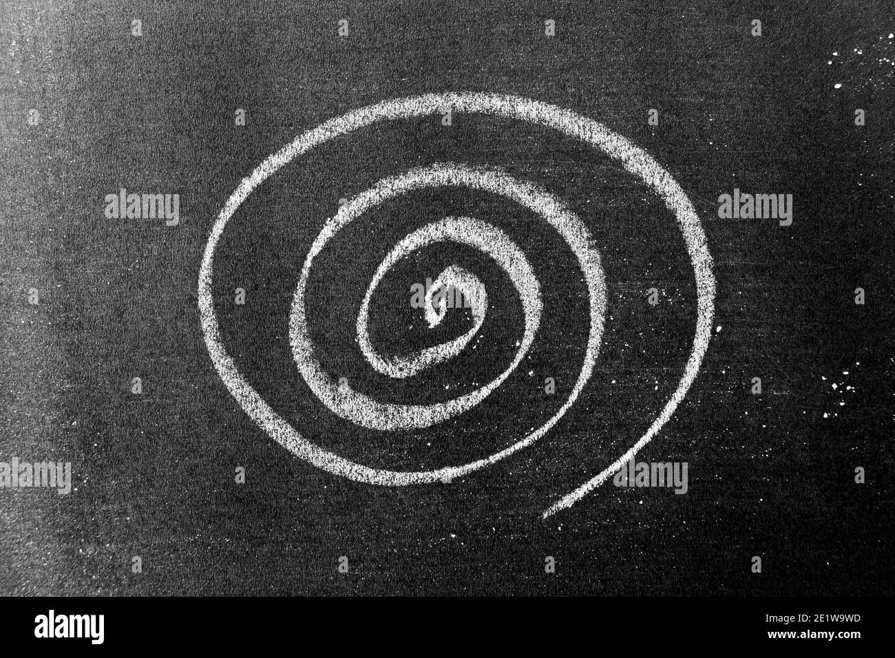 Weiße Kreidehandzeichnung in Spiralform auf schwarzem Bretterhintergrund Stockfoto