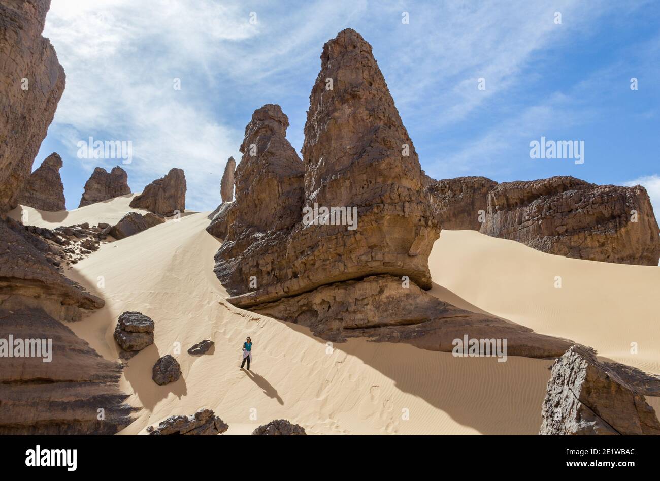Frau, die den Hügel in der Wüste hinaufgeht, umgeben von massiven Felsformationen aus der Antike Stockfoto