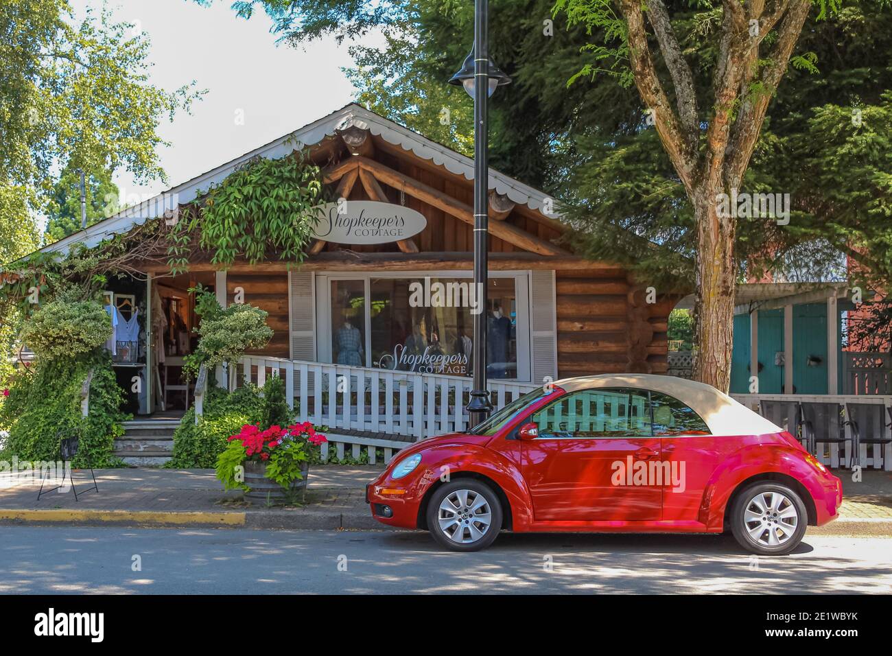 Straßenansicht eines geparkten roten Volkswagen Autos auf einer Seite neben dem Vintage-Shop. Stockfoto