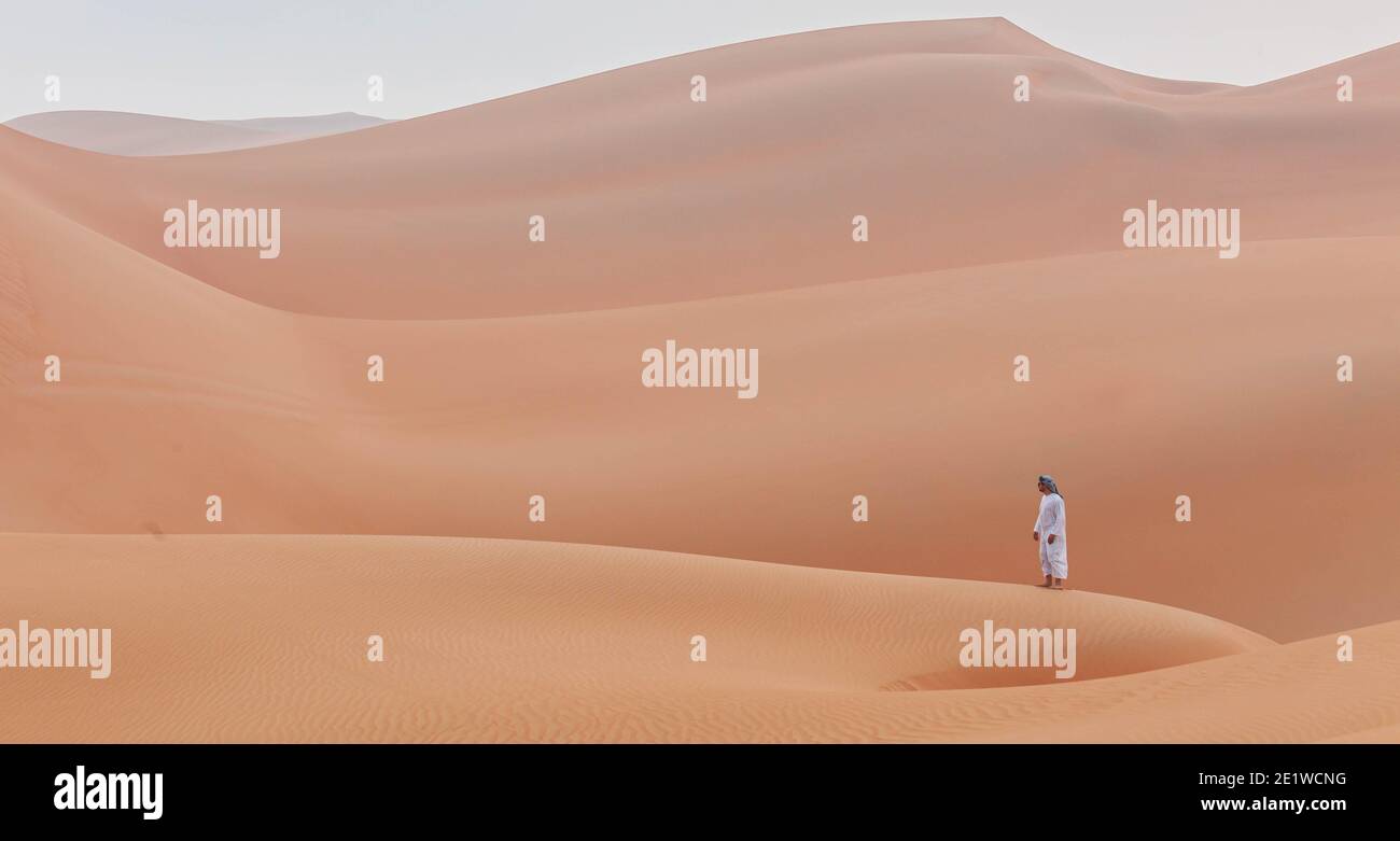 arabischer Mann in Kandoura über einer Düne und schaut zu Der Horizont in der arabischen Wüste Stockfoto