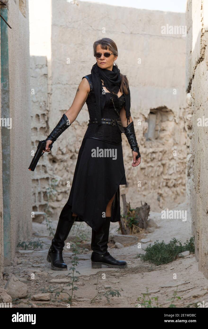 Frau mittleren Alters trägt Steampunk Kostüm der Freiheit Kämpfer in Ihr altes zerstörtes Dorf Stockfoto