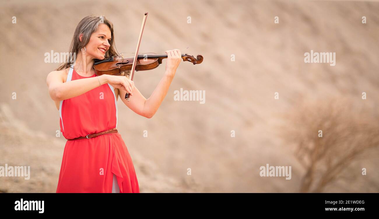 Schöne Europäische Dame spielt Geige in den Bergen Stockfoto