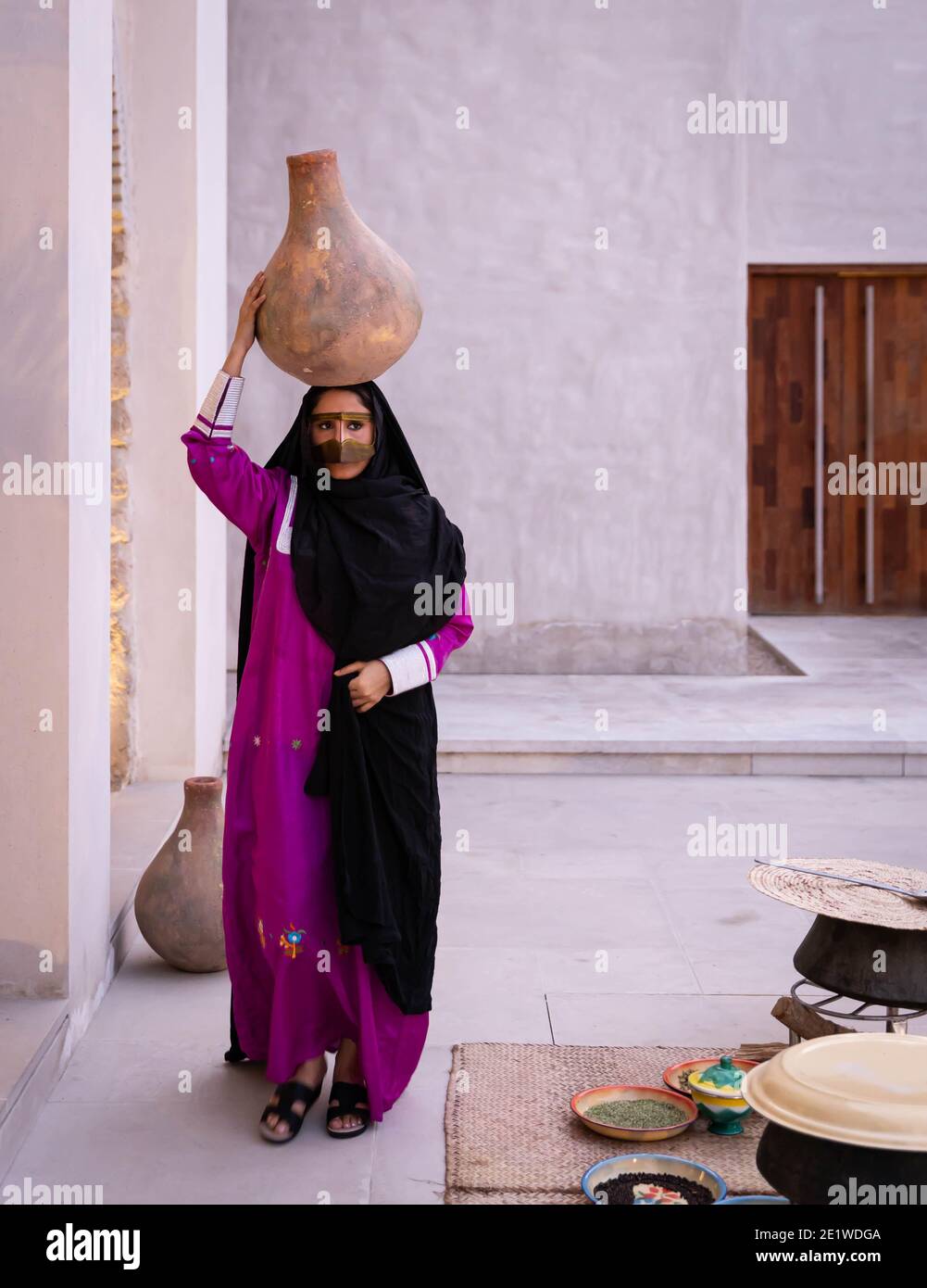 Emarati Dame in traditionellen Kleidern hält ein Glas über ihr Kopf und Roaming rund um das Haus Stockfoto
