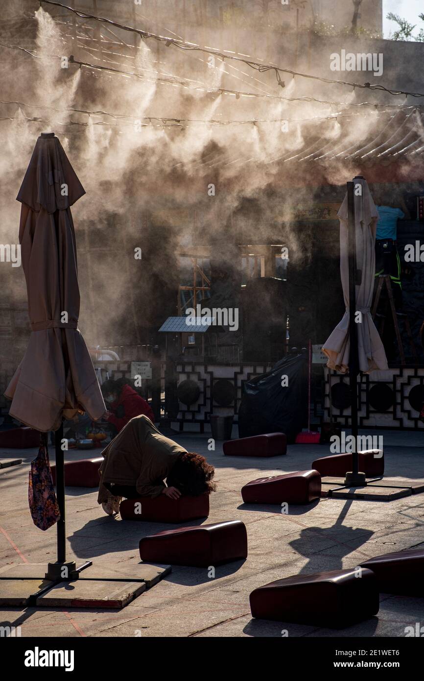 Eine Person gibt ein Opfer im Innenhof des Wong Tai Sin Tempels in Hongkong Stockfoto