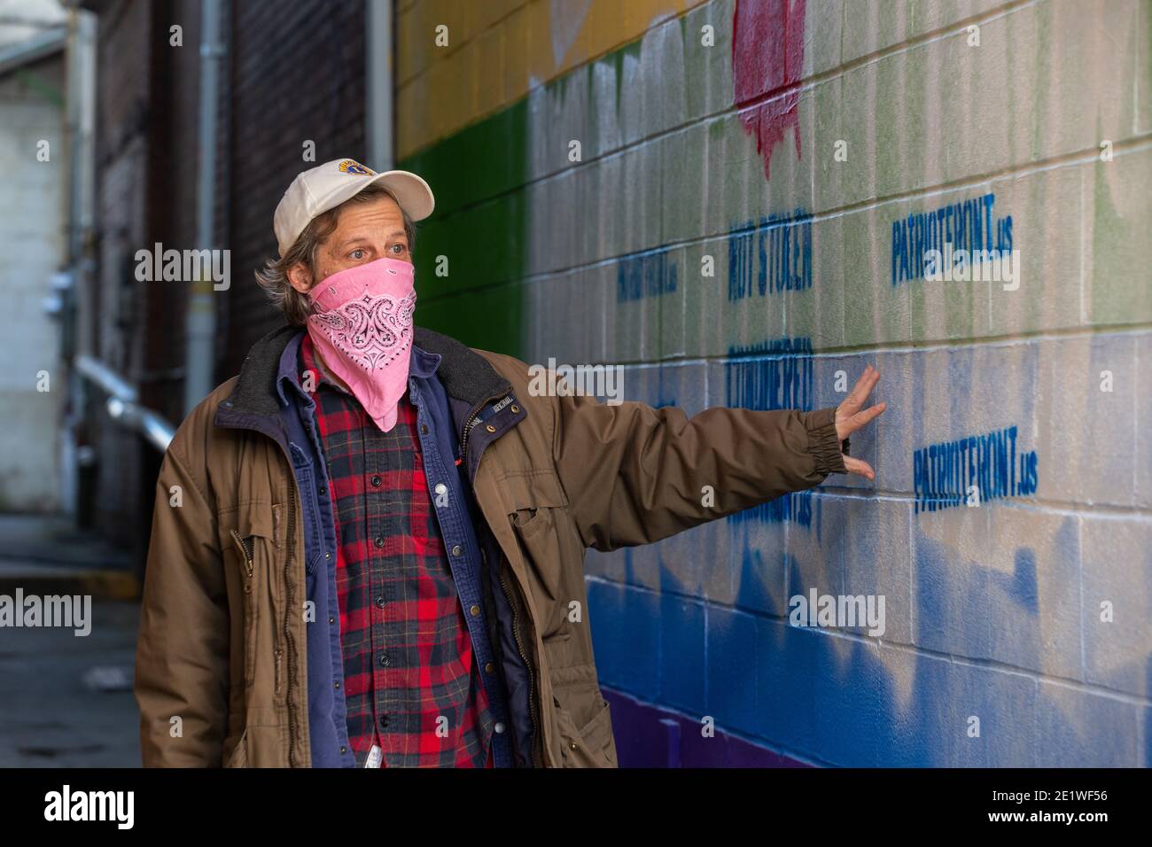 Bryce Taylor, Besitzer von Jake's Cards and Games, schaut sich die weißen nationalistischen Graffiti an, die auf dem Pride-Wandgemälde an der Außenseite seines Unternehmens stehen.Dutzende von Community-Mitgliedern versammelten sich bei Jake's Cards and Games, um das defaced Pride-Wandbild auf der Seite des Unternehmens neu zu malen. Freiwillige wechselten sich ab, um die sprühgemalten Botschaften der weißen nationalistischen Gruppe Patriot Front zu übermalen. Stockfoto