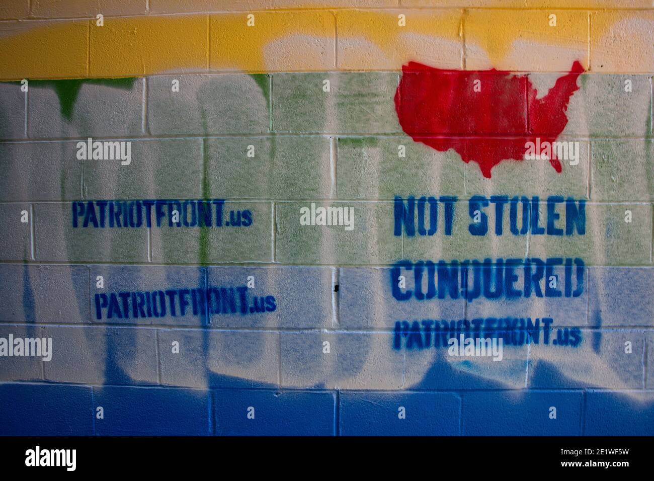 Ein Pride-Wandgemälde an der Außenseite von Jakes Karten- und Spielgeschäft wurde mit schablonierten weißen nationalistischen Nachrichten entstellt.Dutzende von Gemeinschaftsmitgliedern versammelten sich bei Jakes Karten und Spielen, um das defaced Pride-Wandbild auf der Seite des Geschäfts neu zu malen. Freiwillige wechselten sich ab, um die sprühgemalten Botschaften der weißen nationalistischen Gruppe Patriot Front zu übermalen. Stockfoto
