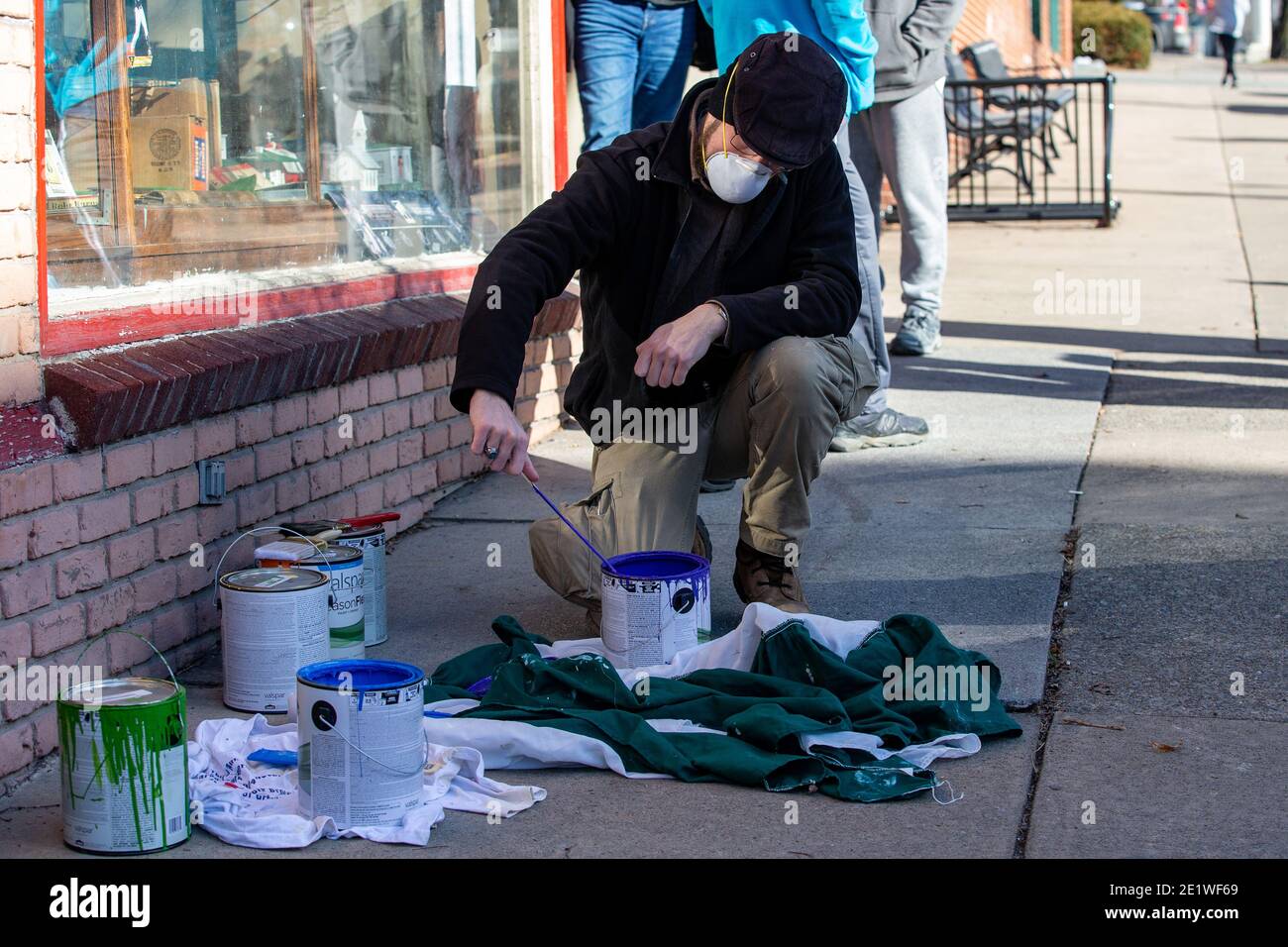 Ein Freiwilliger bereitet Farbe vor, um ein Pride-Wandgemälde neu zu malen, das mit weißen nationalistischen Graffiti besprüht wurde.Dutzende von Community-Mitgliedern versammelten sich bei Jake's Cards and Games, um das defaced Pride-Wandbild auf der Seite des Unternehmens neu zu malen. Freiwillige wechselten sich ab, um die sprühgemalten Botschaften der weißen nationalistischen Gruppe Patriot Front zu übermalen. Stockfoto