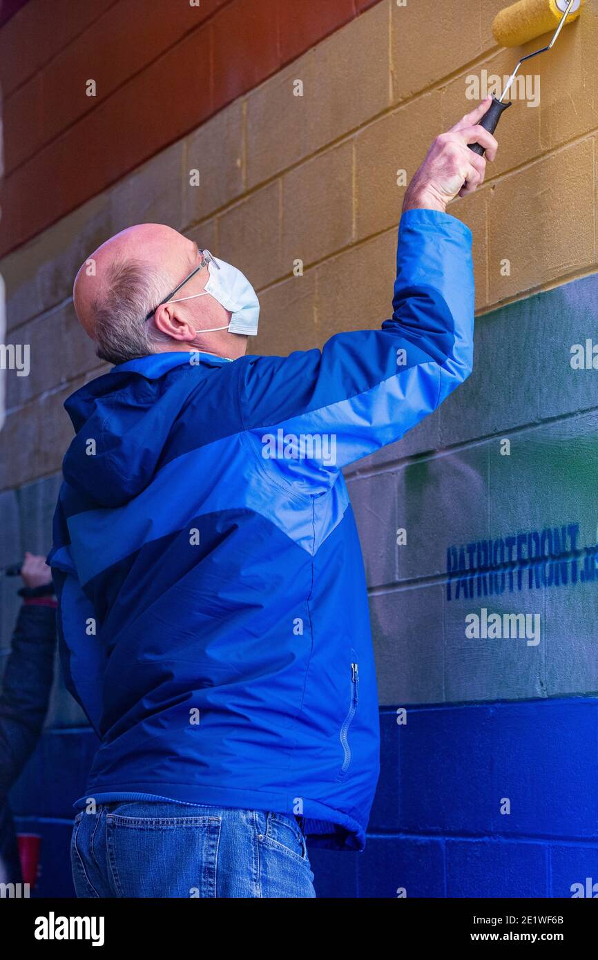 Centre County Commissioner Mark Higgins hilft, ein Pride-Wandgemälde neu zu malen, das mit weißen supremacist-Botschaften entstellt wurde.Dutzende von Community-Mitgliedern versammelten sich bei Jake's Cards and Games, um das Defaced Pride-Wandbild auf der Seite des Unternehmens neu zu malen. Freiwillige wechselten sich ab, um die sprühgemalten Botschaften der weißen nationalistischen Gruppe Patriot Front zu übermalen. Stockfoto