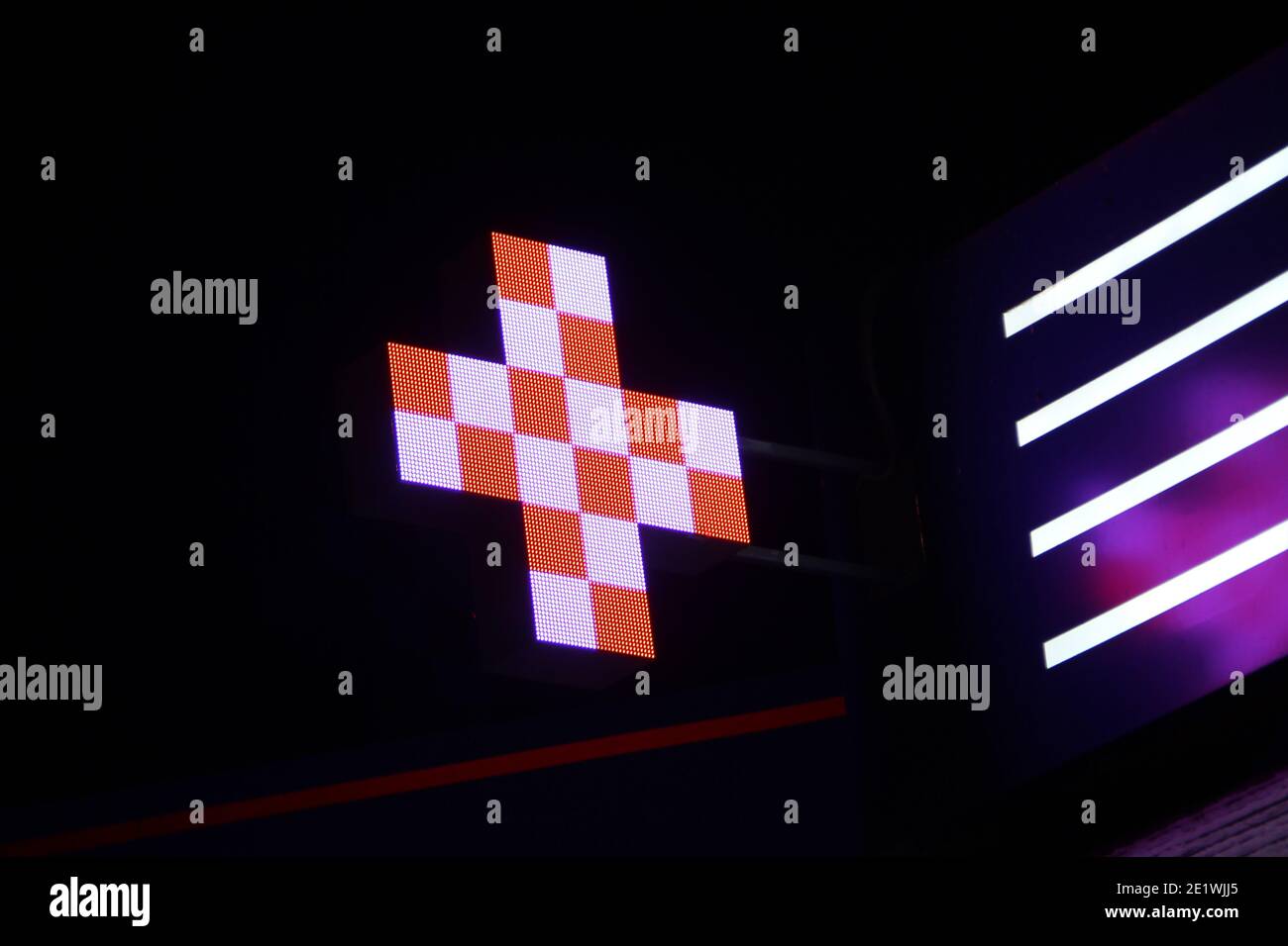 Leuchtendes Pixelkreuz von LED-Lampen auf schwarzem Hintergrund. Kreuz mit einem Muster in weiß und orange Symbol für Gesundheit, Medizin, Selbstversorgung. Stock Foto mit Stockfoto