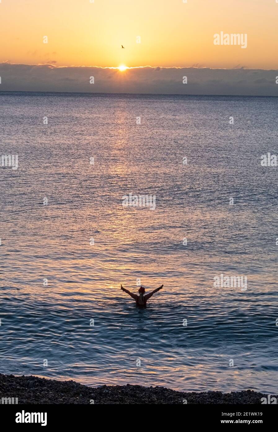Schwimmer im Meer begrüßen den Sonnenaufgang, an einem kalten Dezember im Winter, in Hastings, am Xmas Day, East Sussex, Großbritannien Stockfoto