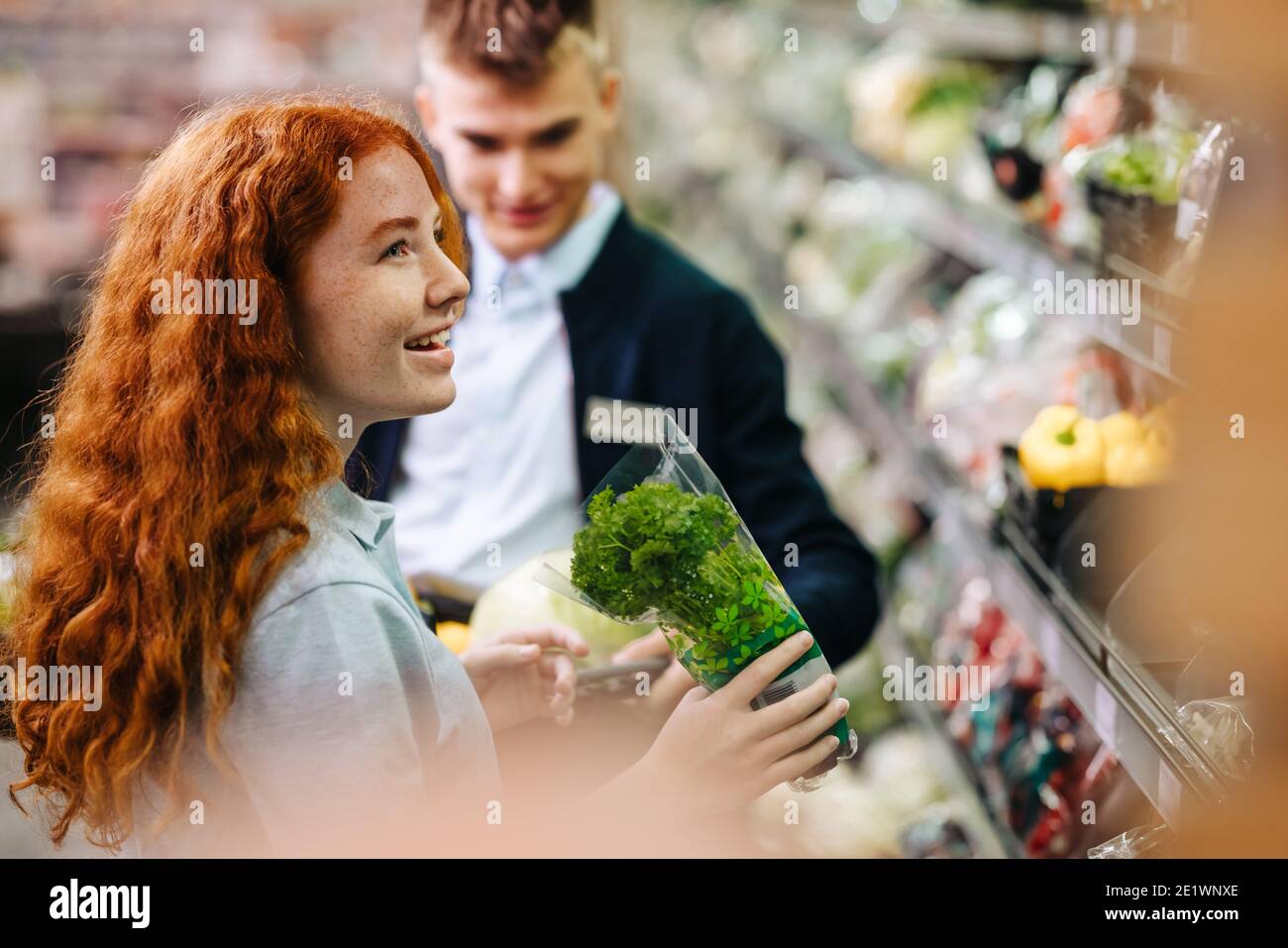 Zwei Personen, die in der Produzenteil eines Supermarkts arbeiten. Mann und Frau Supermarkt Auszubildende Mitarbeiter bei der Arbeit halten frisches Gemüse während der Einlage Stockfoto