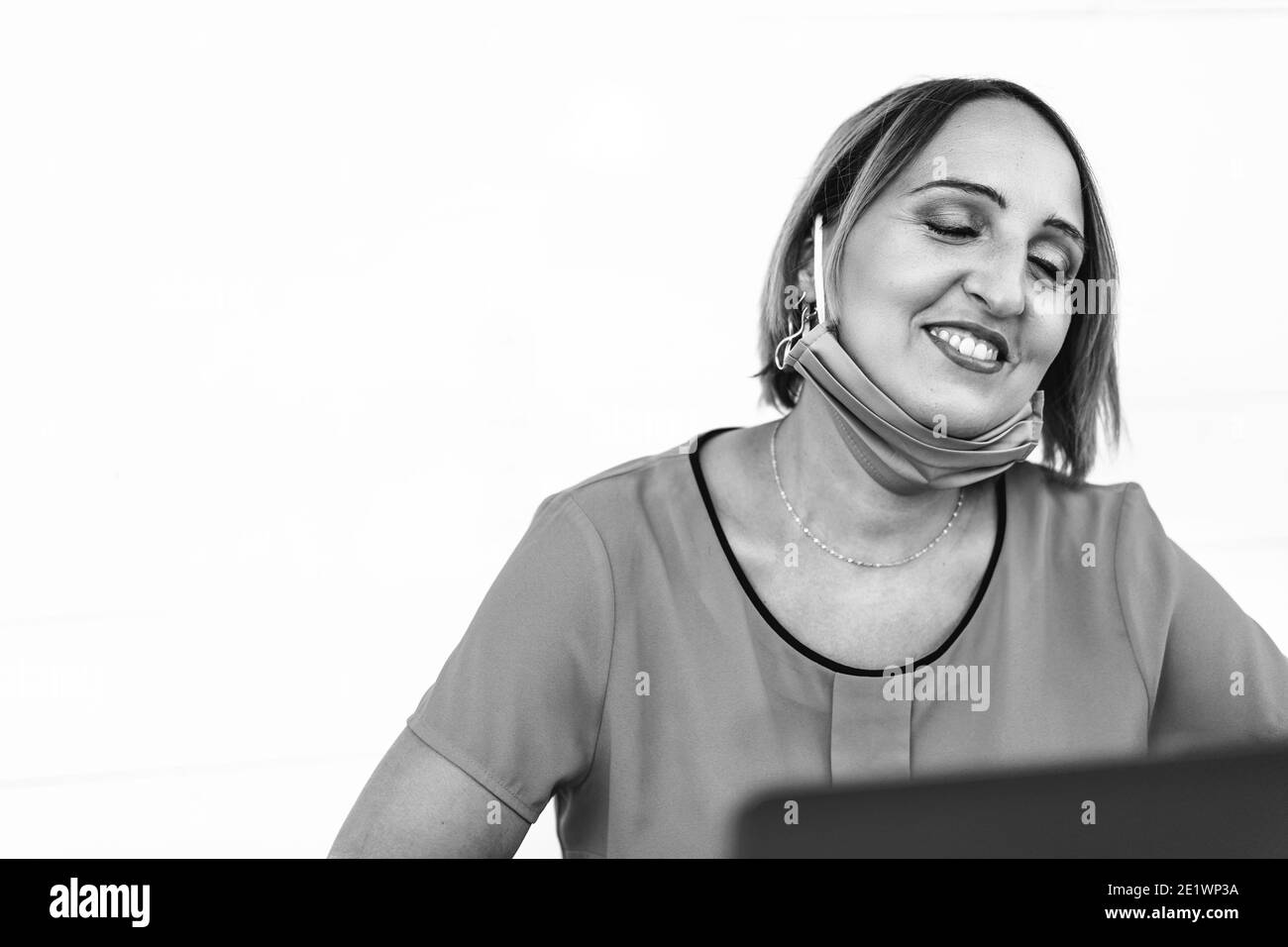 Lächelnde Frau 40 Jahre alt trägt offene Schutzmaske Mit Laptop während des Endes des Coronavirus-Ausbruchs - Weiblich Unternehmer oder Influencer h Stockfoto