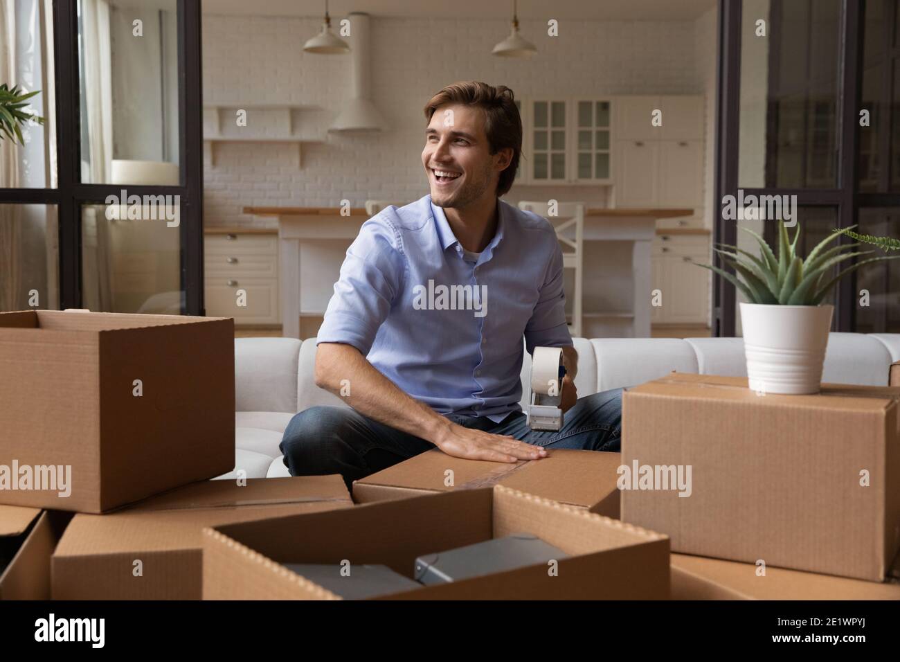 Lächelnder Mann fühlt sich aufgeregt Verpackung Umzug in ein neues Zuhause Stockfoto