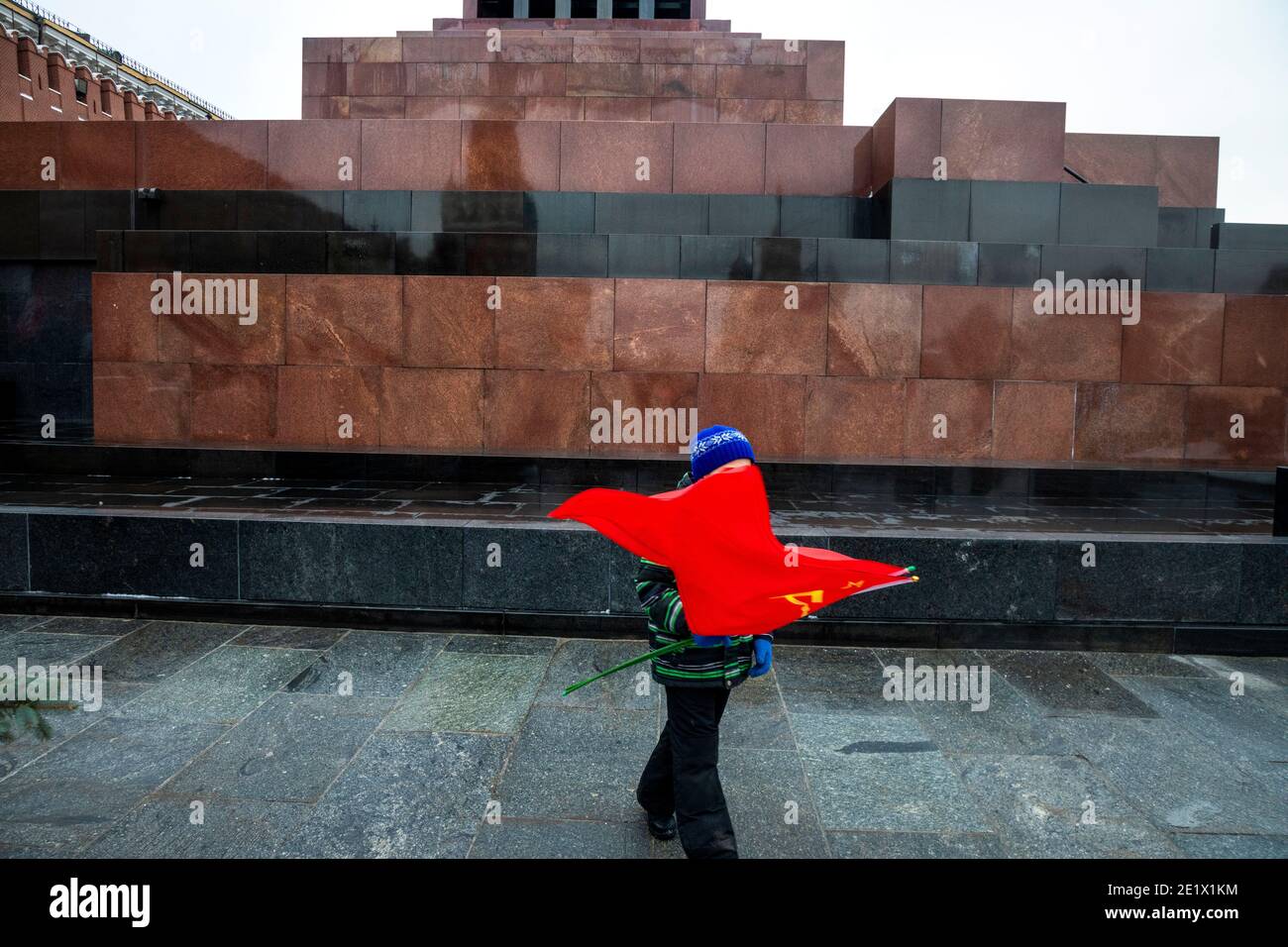 Moskau, Russland. 21. Dezember 2020 EIN kleiner Junge hält die Flagge der Sowjetunion am Fuße des Wladimir-Lenin-Mausoleums auf dem Roten Platz während der Blumenauflegung der Kommunisten am Grab von Josef Stalin in Moskau, Russland Stockfoto