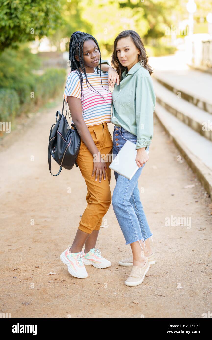Zwei multiethnische Frauen posieren zusammen mit farbenfroher Freizeitkleidung Stockfoto