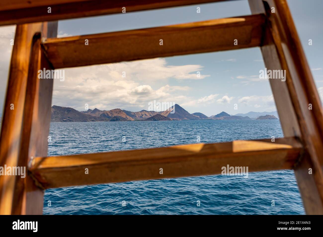 Panoramablick von einem hölzernen Kreuzfahrtschiff in türkis Wasser und eine Insel am Horizont in Komodo National Marine Park Stockfoto