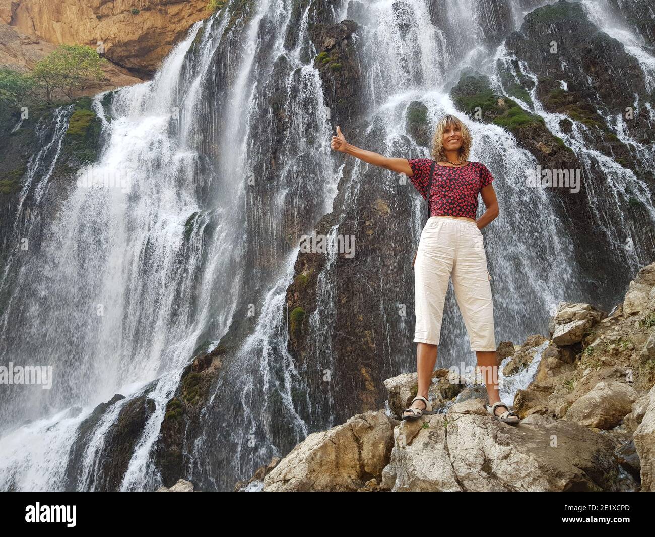 Lächelndes Mädchen vor massiven Kapuzbasi Wasserfall. Stockfoto