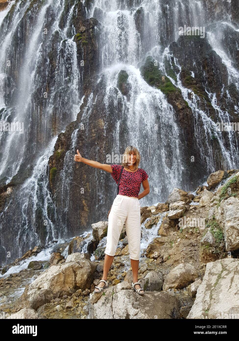 Glückliches Mädchen vor einem massiven Kapuzbasi Wasserfall. Stockfoto