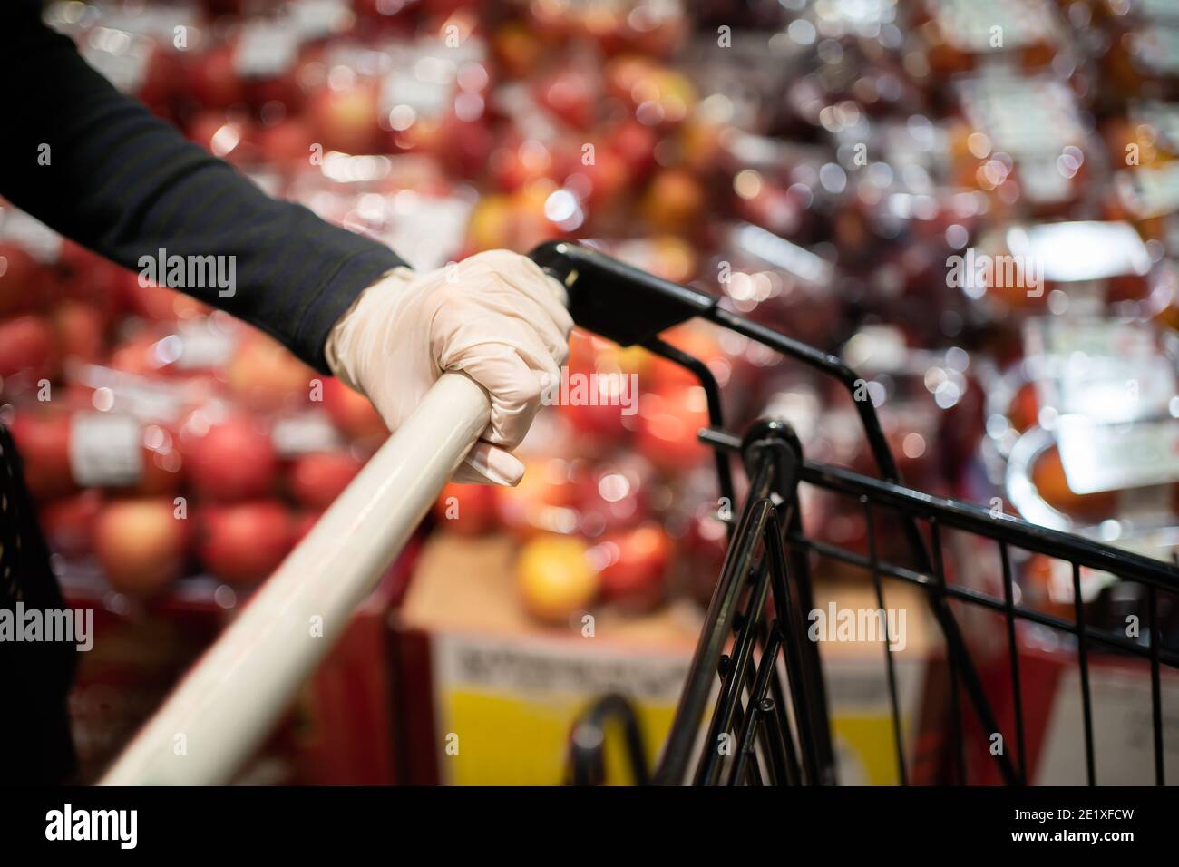 Menschen greifen den Griff eines Einkaufswagens mit Gummihandschuhen während Covid-19 Pandemie Stockfoto