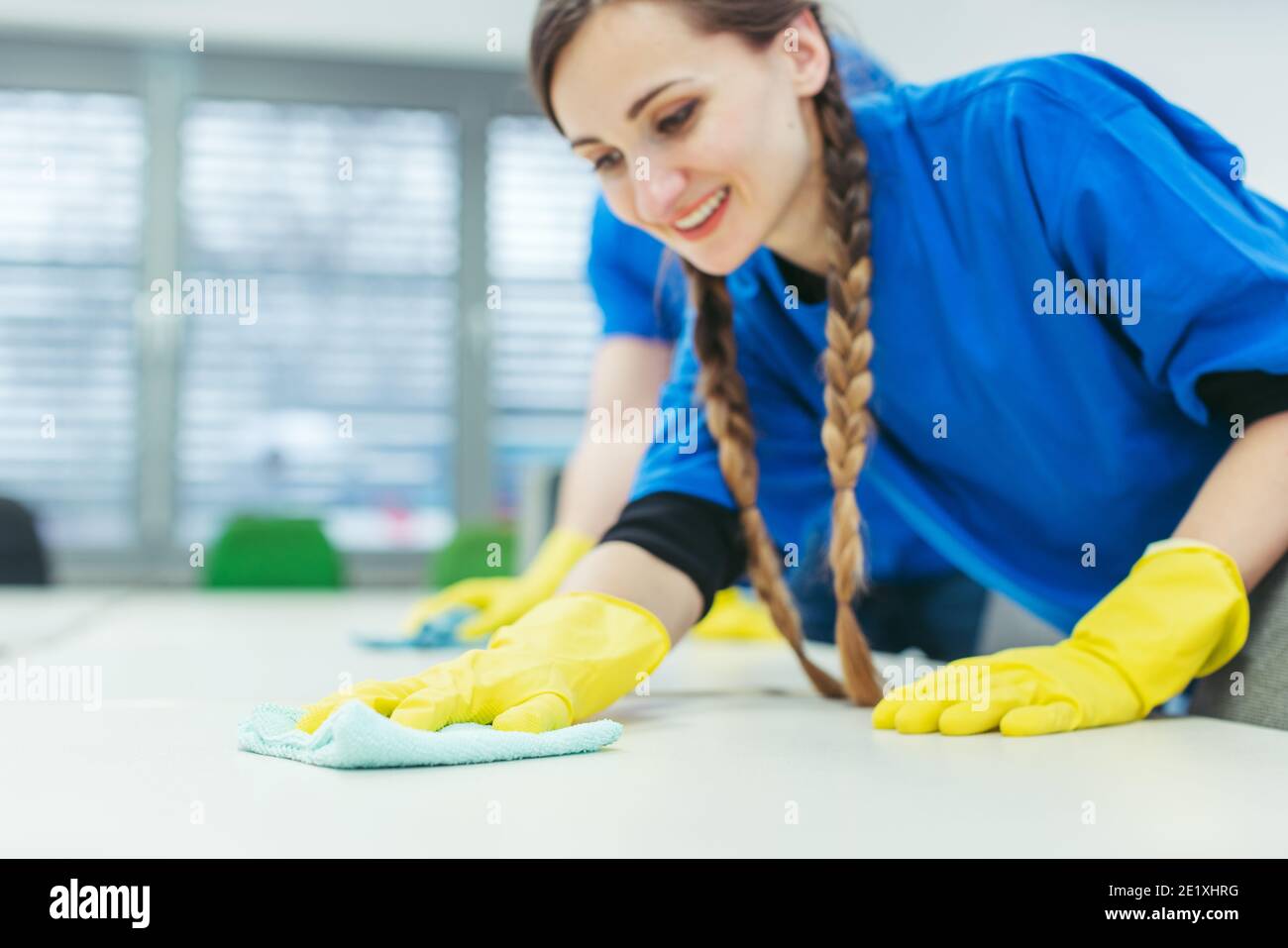 Reinigungspersonal, das Schreibtische abwischt Stockfoto