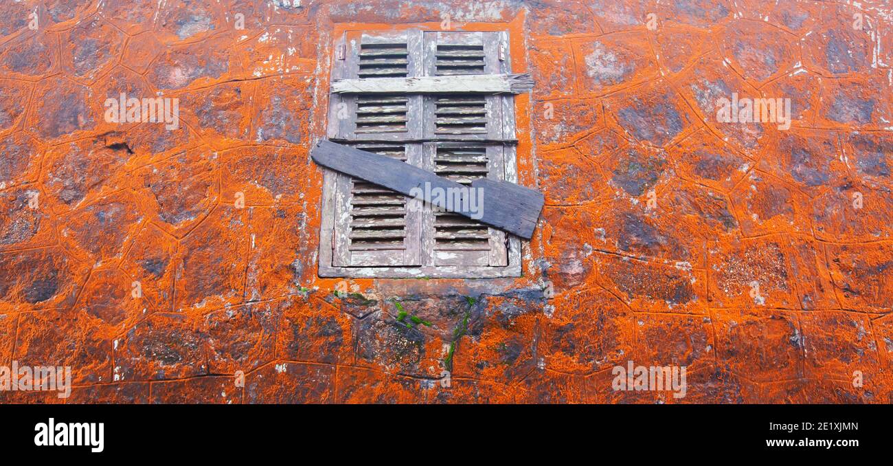 Abstrakte orange Flechte wächst auf alten Steinmauer und Holzfenster des Wat Sampov Tempel, Kambodscha. Selektiver Fokus. Stockfoto