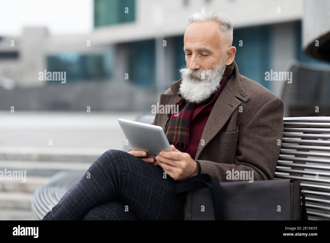 Älterer Geschäftsmann mit langen grauen Bart Lesen auf Pad Stockfoto
