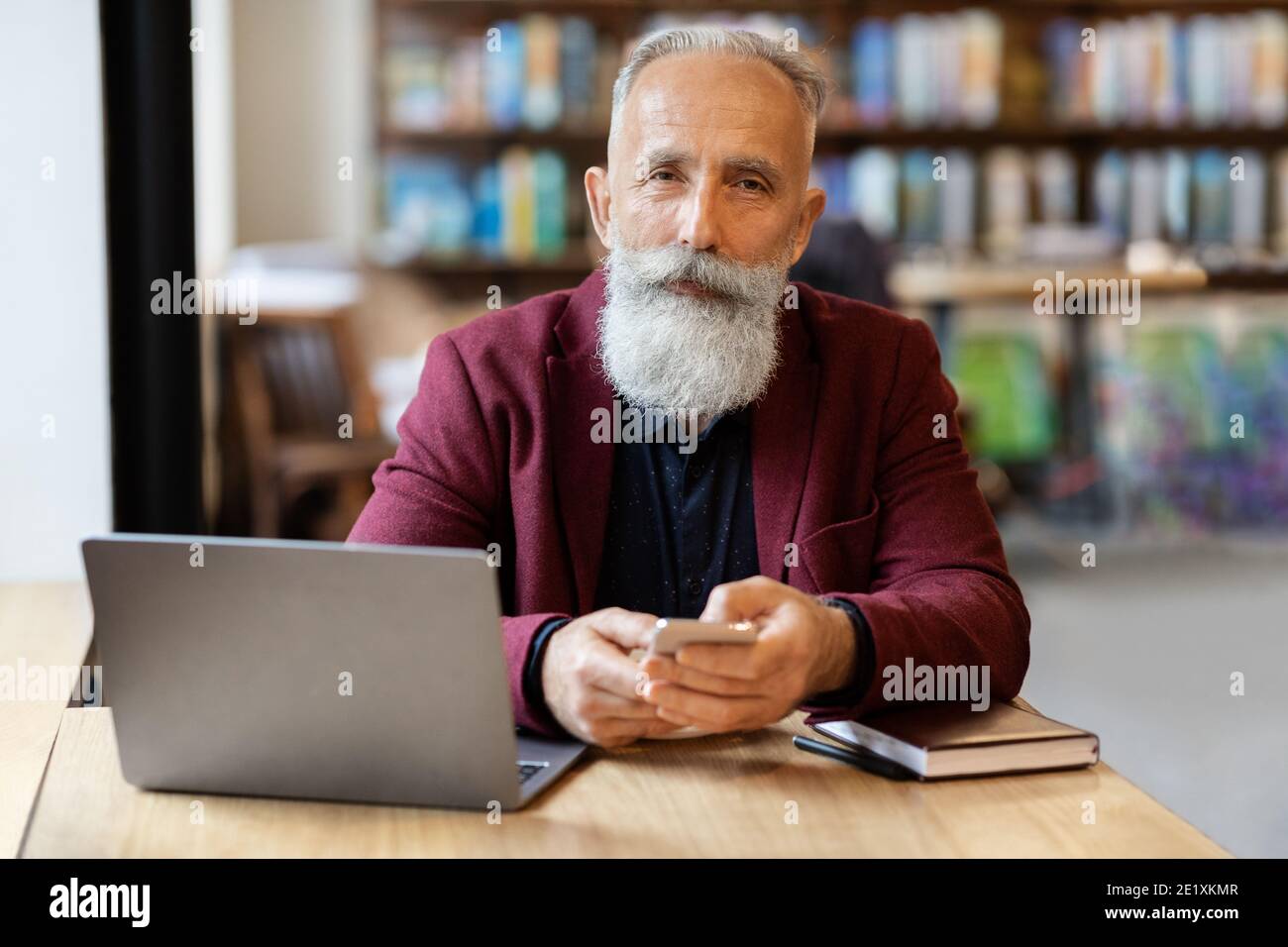 Wohlhabender älterer Mann mit Smartphone im Café Stockfoto