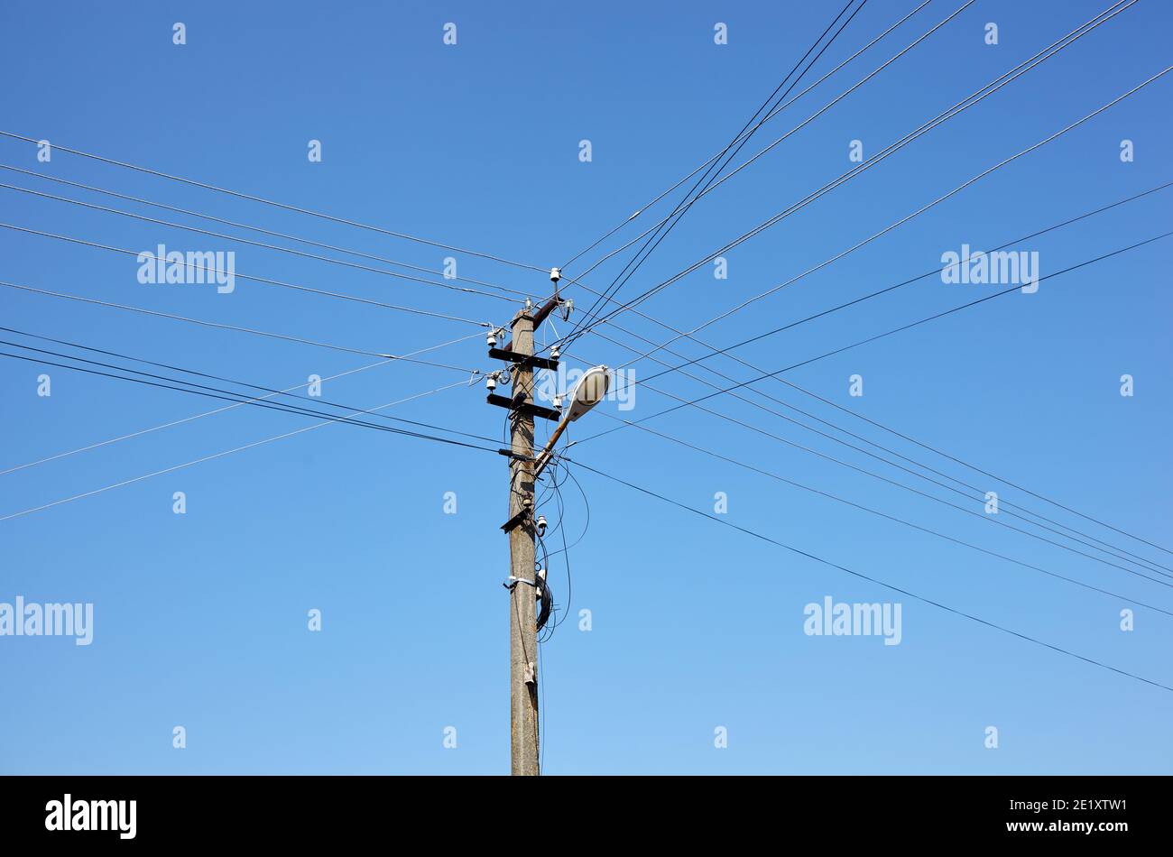 Nahaufnahme der alten Säule an einem Sommertag. Stromlinienpfosten mit Stromkabeln gegen einen klaren blauen Himmel Stockfoto