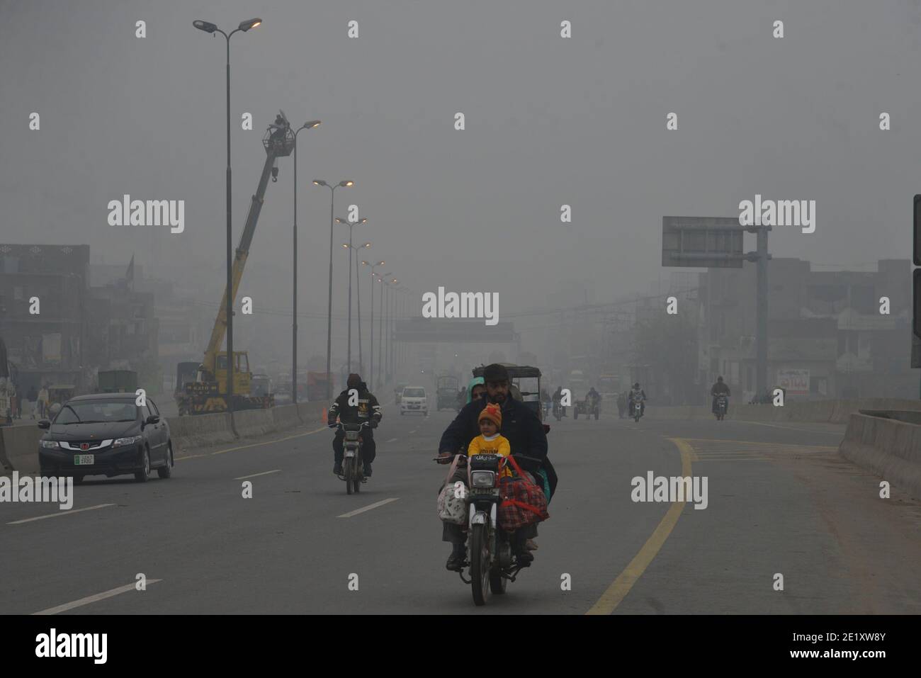 Pakistanische Pendler machen ihren Weg inmitten dichten Nebel auf ein Kalter Wintermorgen in Lahore Stockfoto