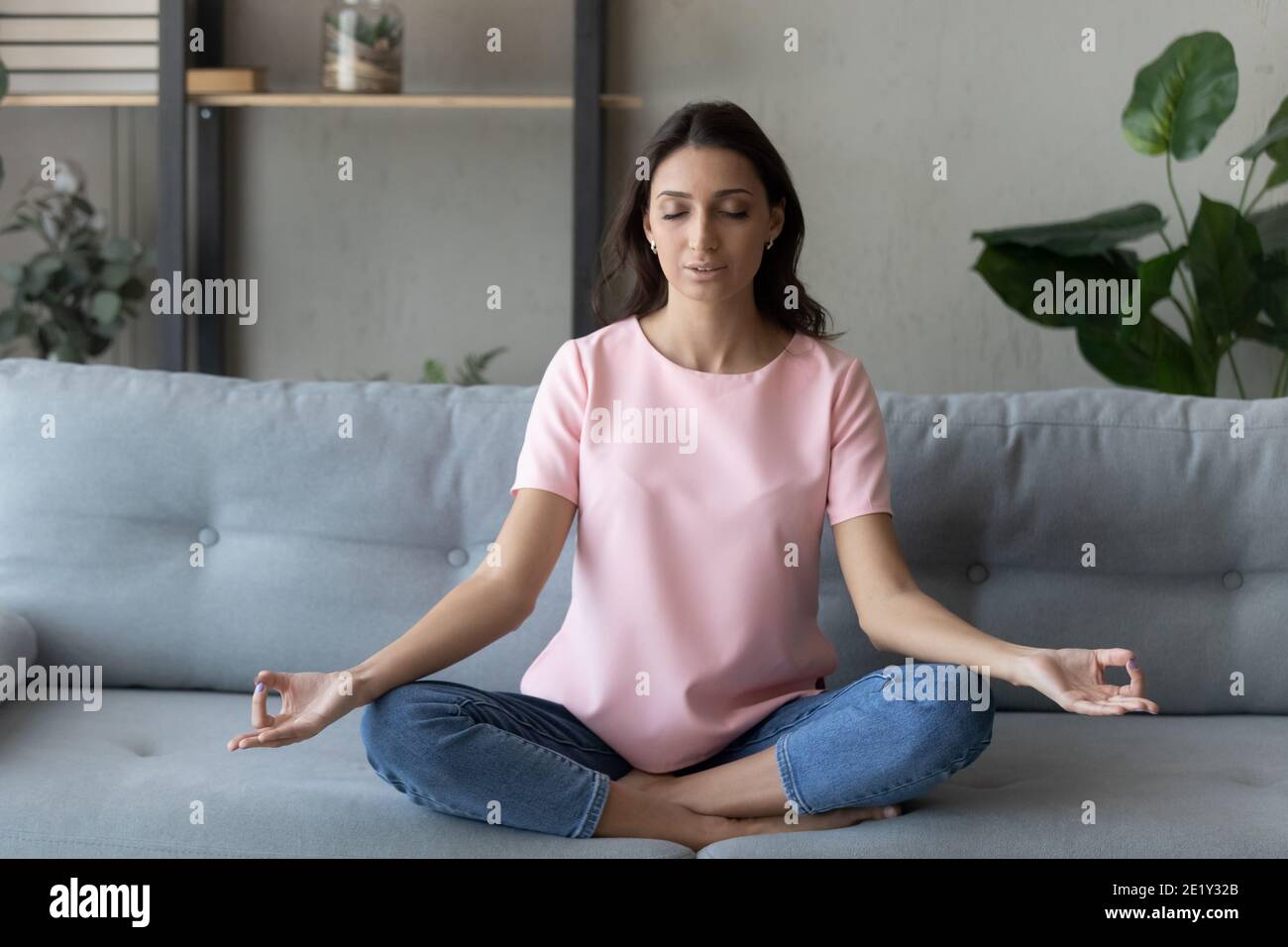 Ruhige ethnische Frau praktiziert Yoga zu Hause Stockfoto