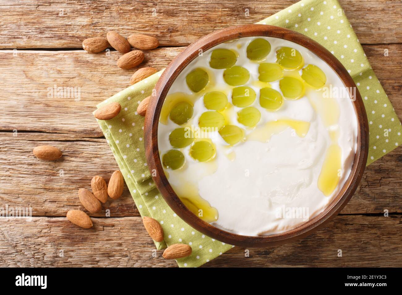 Spanische kalte Suppe aus gehackten Mandeln, Brot und Knoblauch mit grünen Trauben aus der Nähe in einer Schüssel auf dem Tisch serviert. Horizontale Ansicht von oben Stockfoto