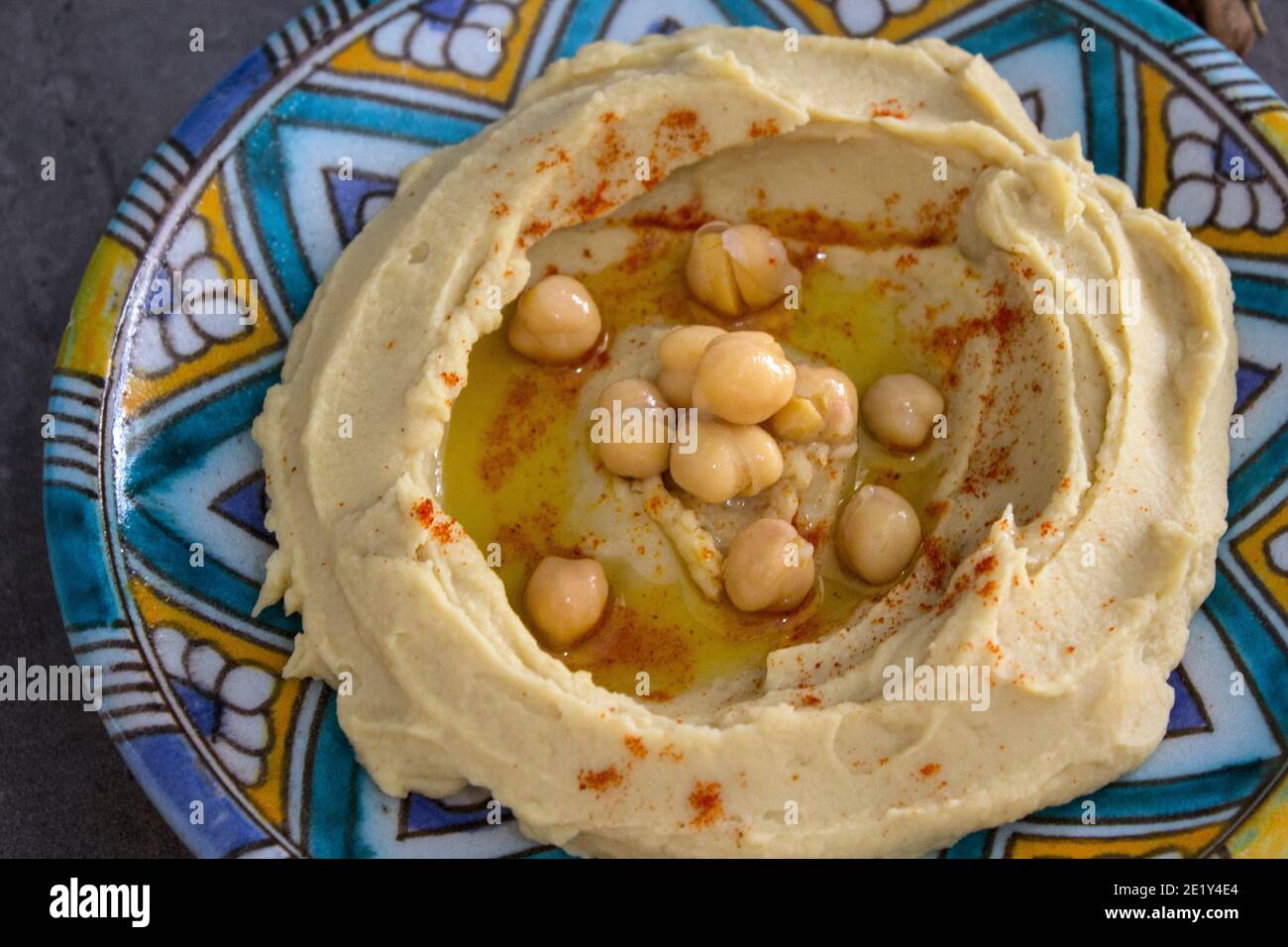 Leckerer Hummus auf buntem Teller. Foto der traditionellen Küche Israels von oben. Ausgewogene Ernährung Konzept. Klassischer israelischer Hummus. Stockfoto