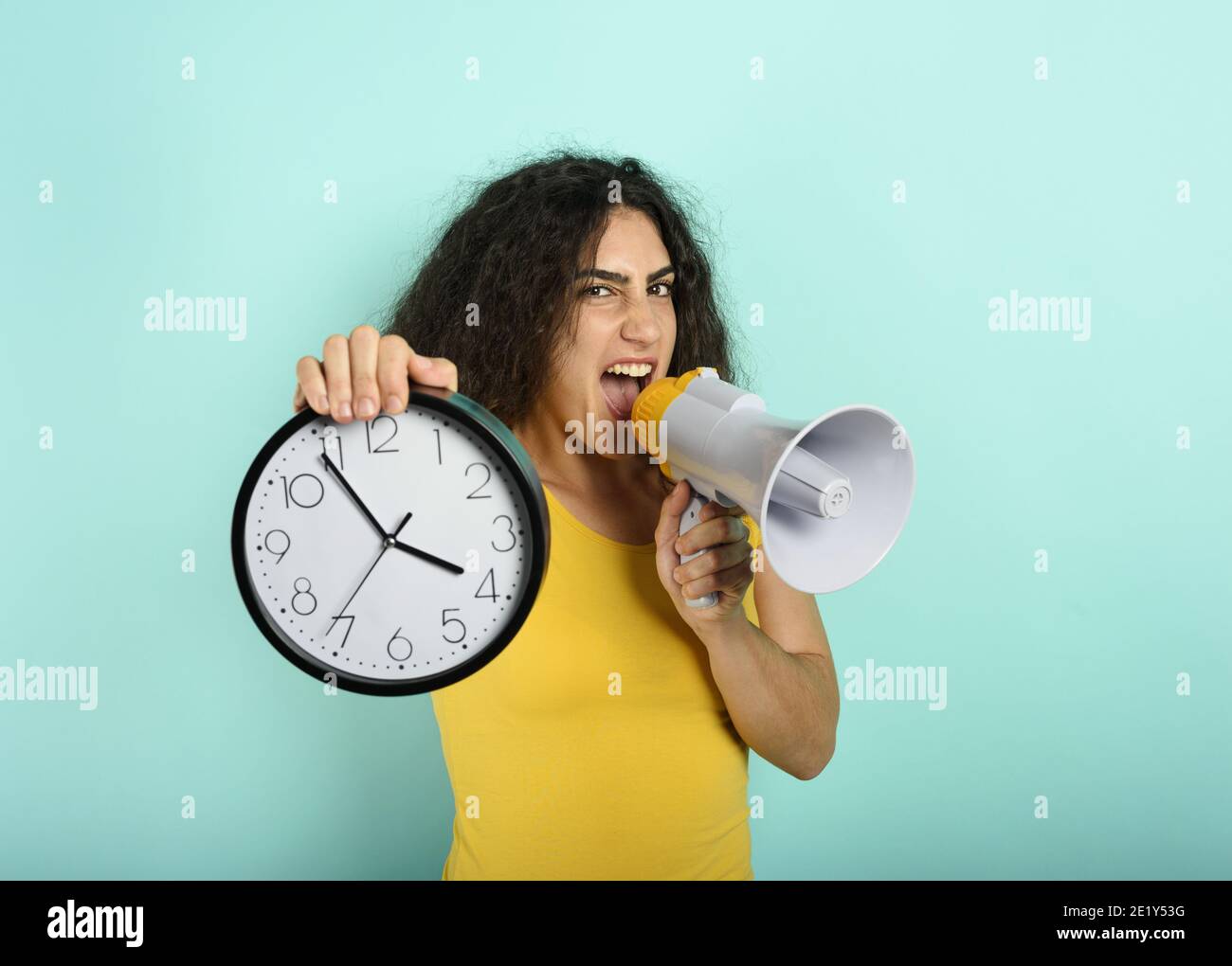 Frau schreit mit Lautsprecher, weil es zu spät ist. Wütend Ausdruck. Cyan Hintergrund Stockfoto