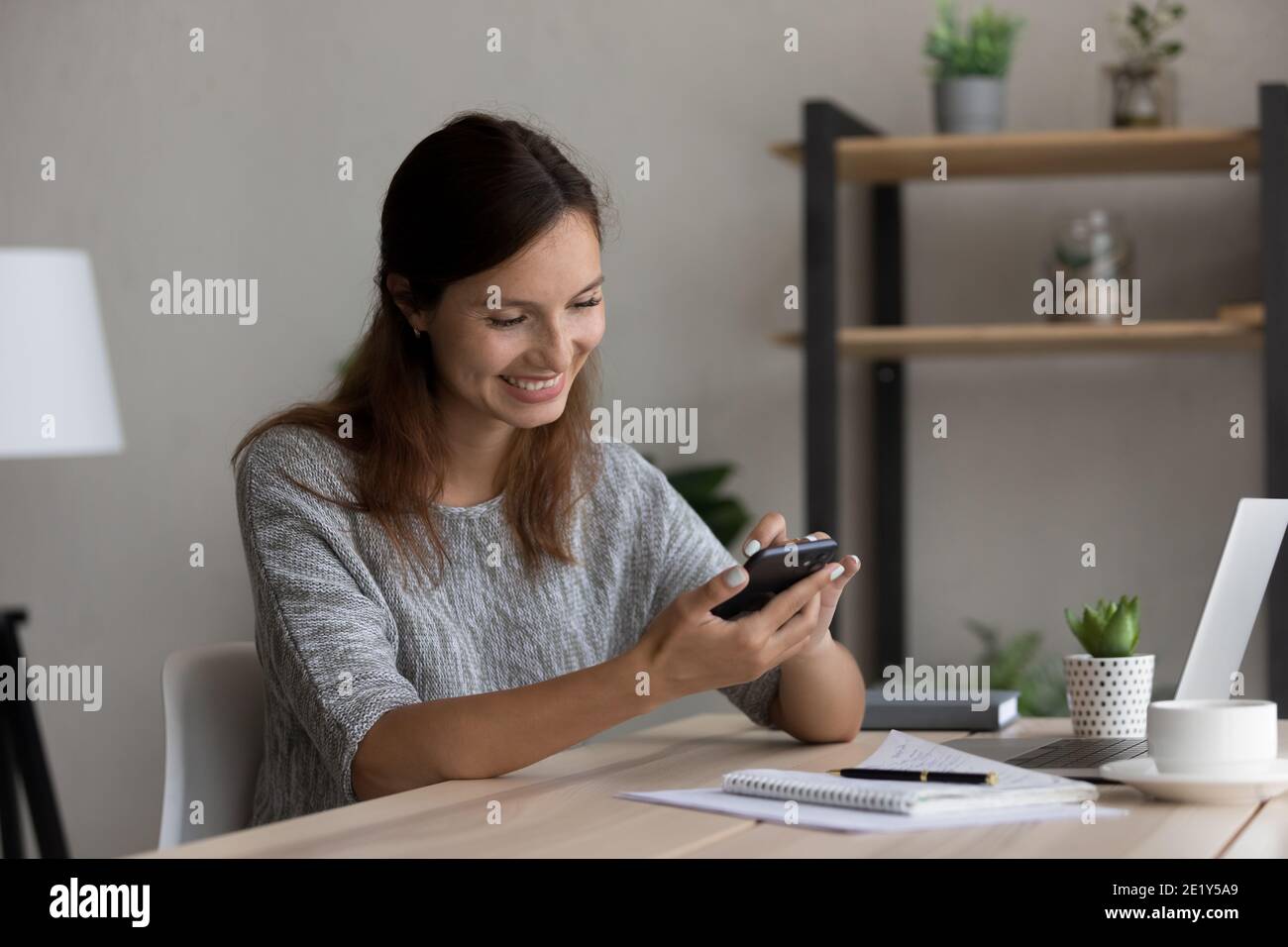 Lächelnde Frau Blick auf Handy-Bildschirm SMS online Stockfoto