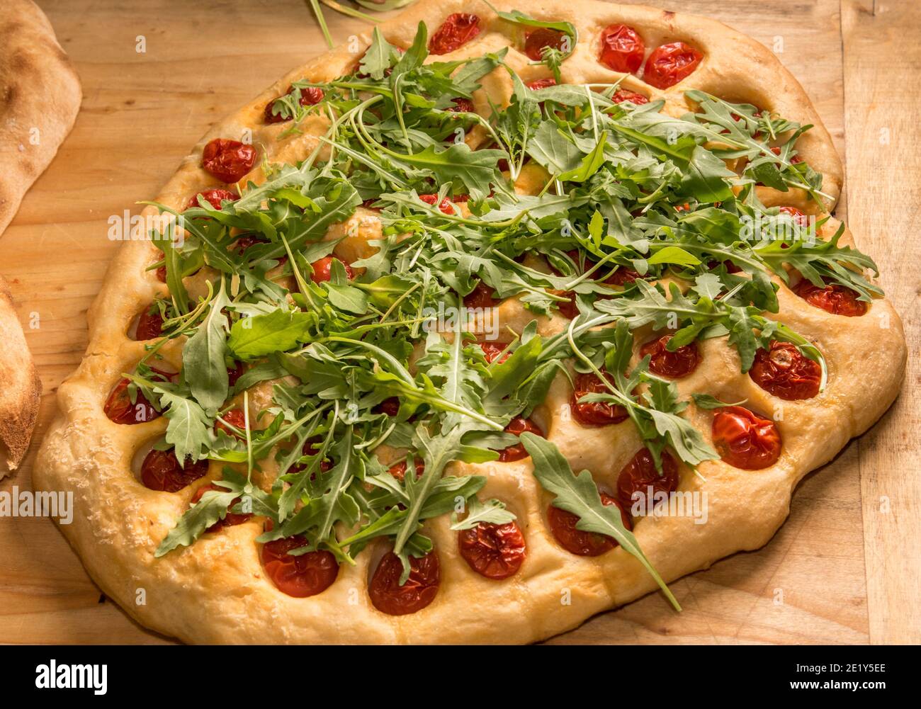 Apulian Focaccia, typische Pizza aus Bari mit Kirschtomaten und Rucola auf Holztisch Stockfoto