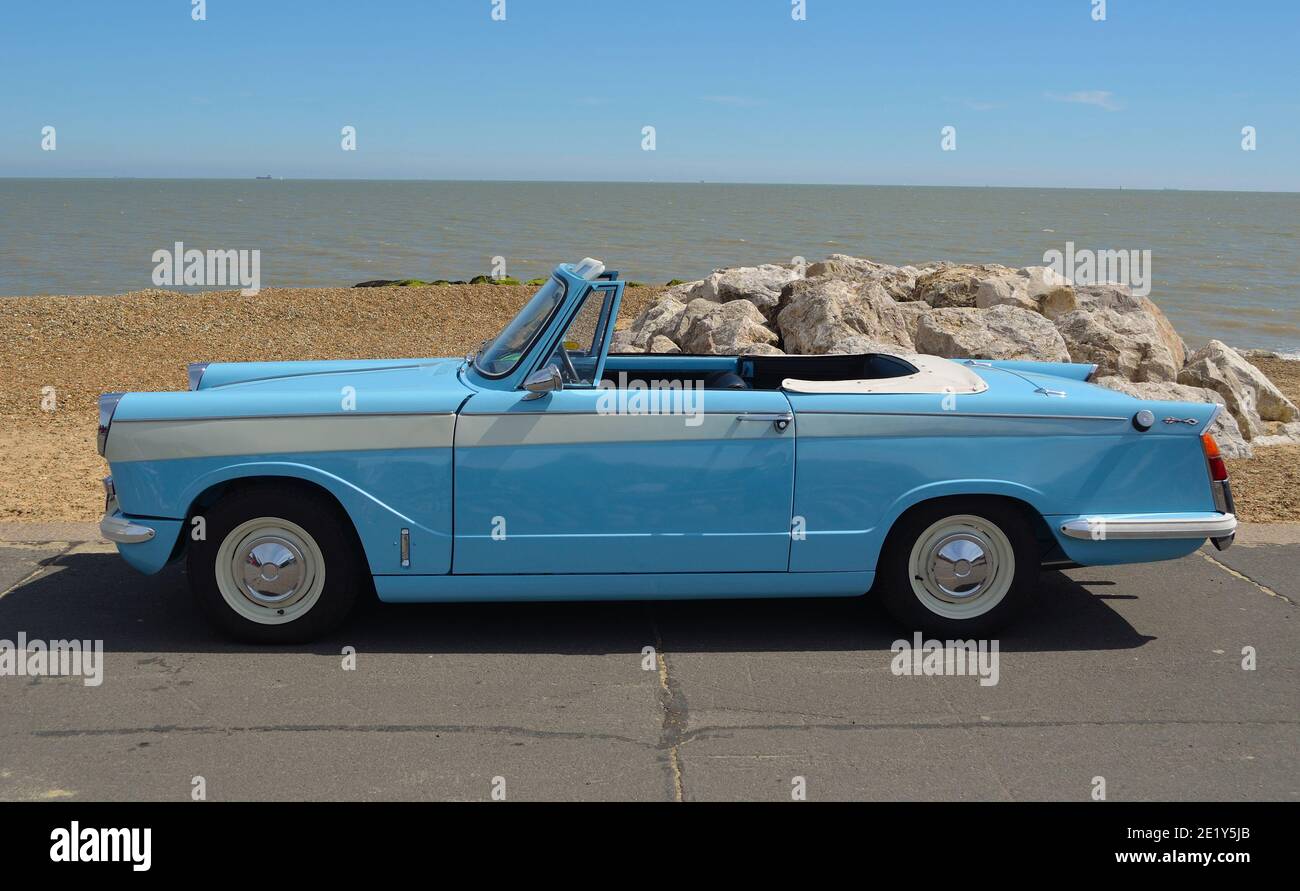 Classic Light Blue Triumph Herald offener Wagen, der an der Strandpromenade geparkt ist. Stockfoto