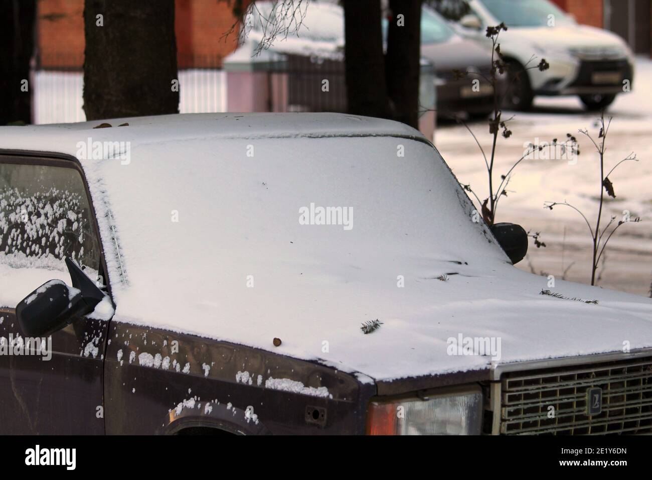 Altes russisches dunkelblaues Schiguli Auto unter einer Schneeschicht. Hochwertige Fotos Stockfoto
