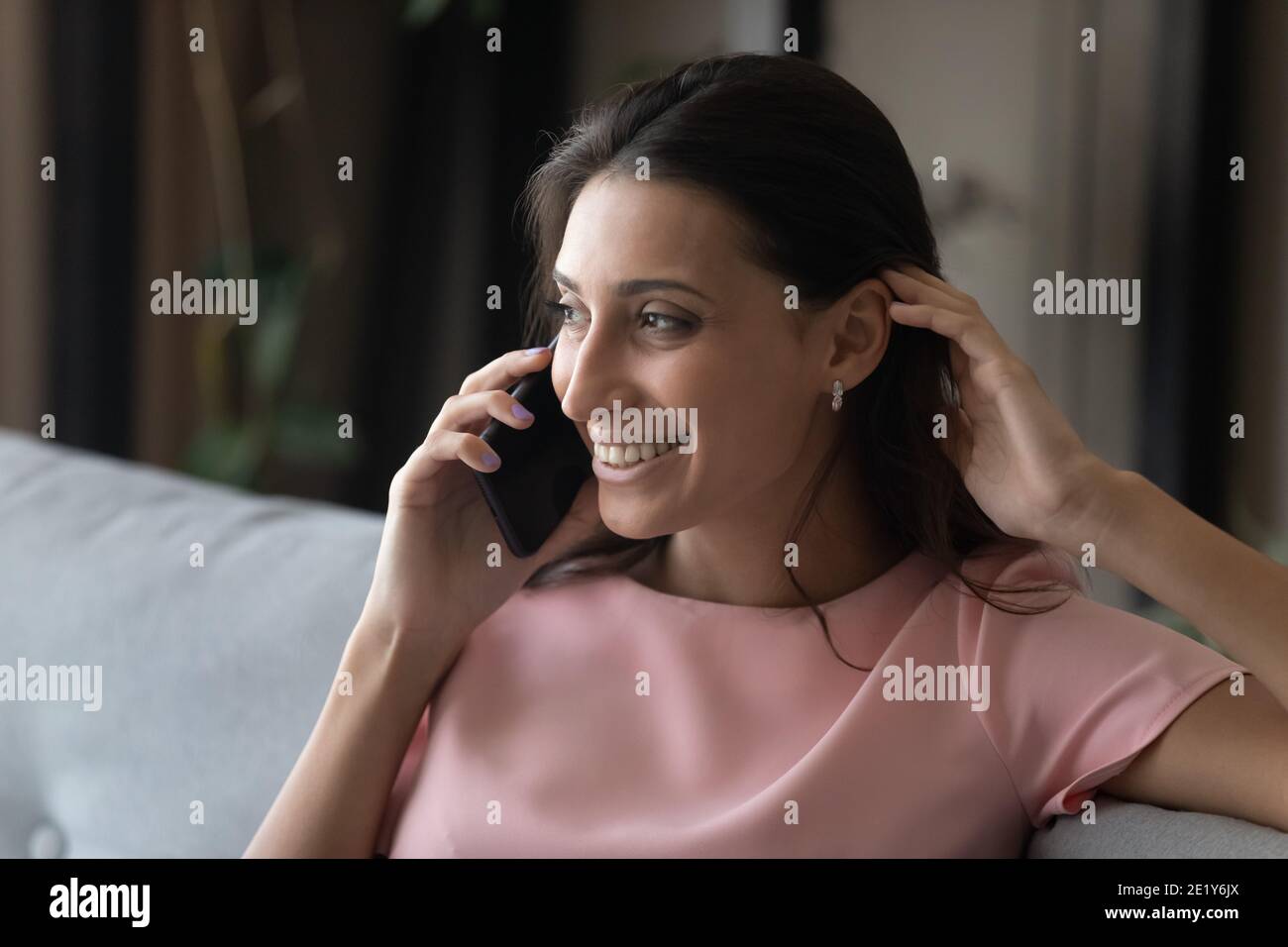 Lächelnde ethnische Frau sprechen zu Hause am Handy Stockfoto