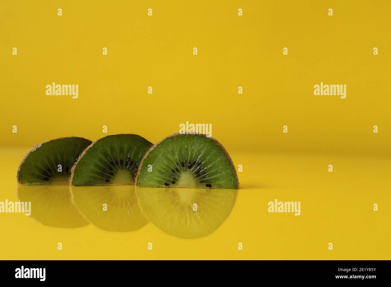 Drei Scheiben Kiwi Hälften liegen in einer Reihe auf Trend iluminaited gelb mit einer Kopie der Platz für Text. Stockfoto