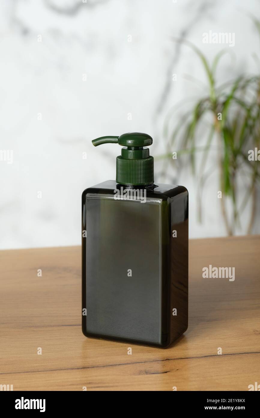 Grüne leere Pumpe kosmetische Flasche mockup ohne Etikett auf dem Tisch im Badezimmer. Luxus Shampoo Spender Verpackung Design. Stockfoto