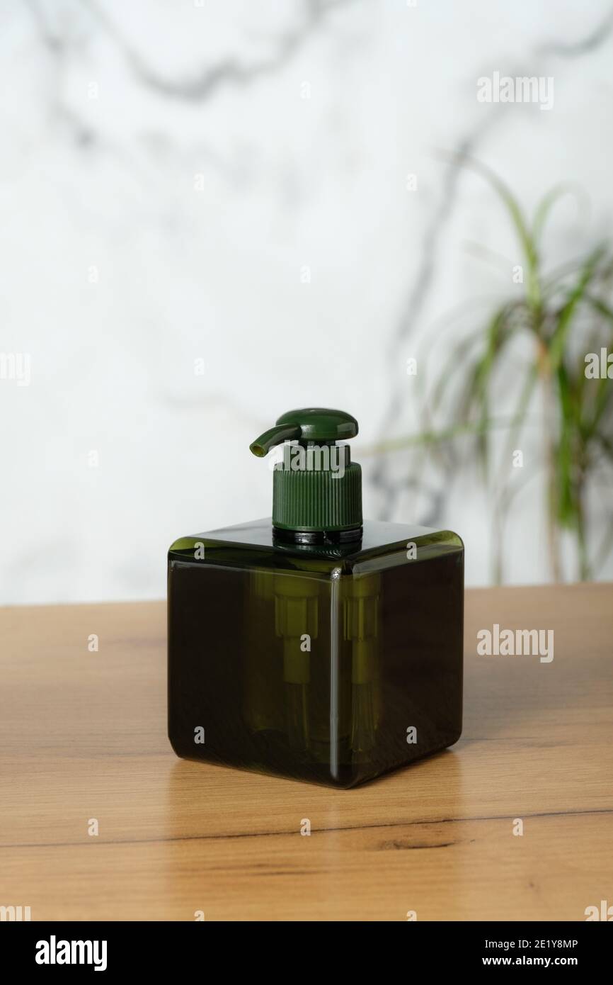 Grüne leere Plastikflasche mit Pumpe auf dem Tisch im Badezimmer. Quadratische Schönheit Produktverpackung für Handwaschseife. Stockfoto