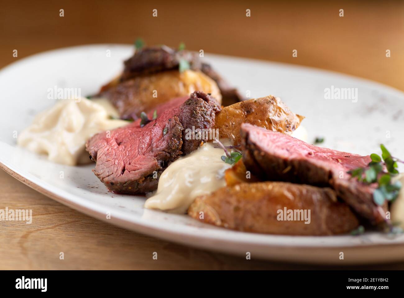 Filet von Mignon auf einem schwarzen Teller auf einem Hintergrund von Gemüse, Gewürzen und Gemüse, auf einem Kupferblech. Nahaufnahme. Stockfoto