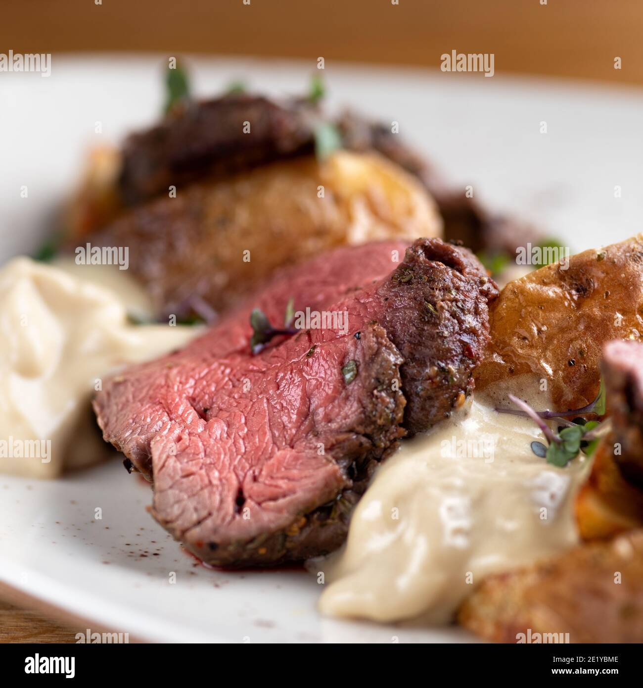 Filet von Mignon auf einem schwarzen Teller auf einem Hintergrund von Gemüse, Gewürzen und Gemüse, auf einem Kupferblech. Nahaufnahme. Stockfoto