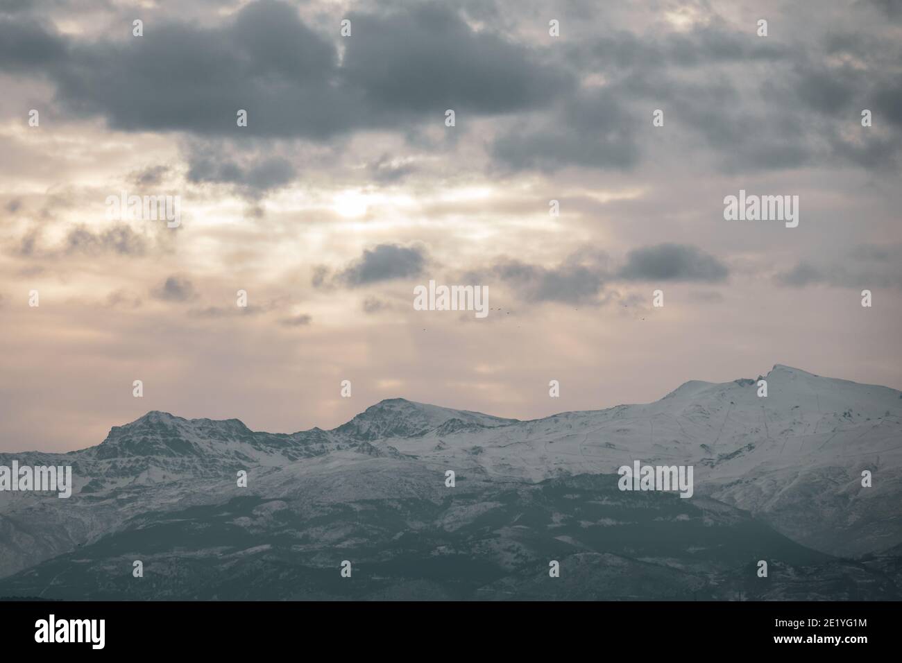 Blick auf die höchsten Gipfel der Sierra Nevada (Granada, Spanien) an einem bewölkten Wintermorgen bei Sonnenaufgang Stockfoto